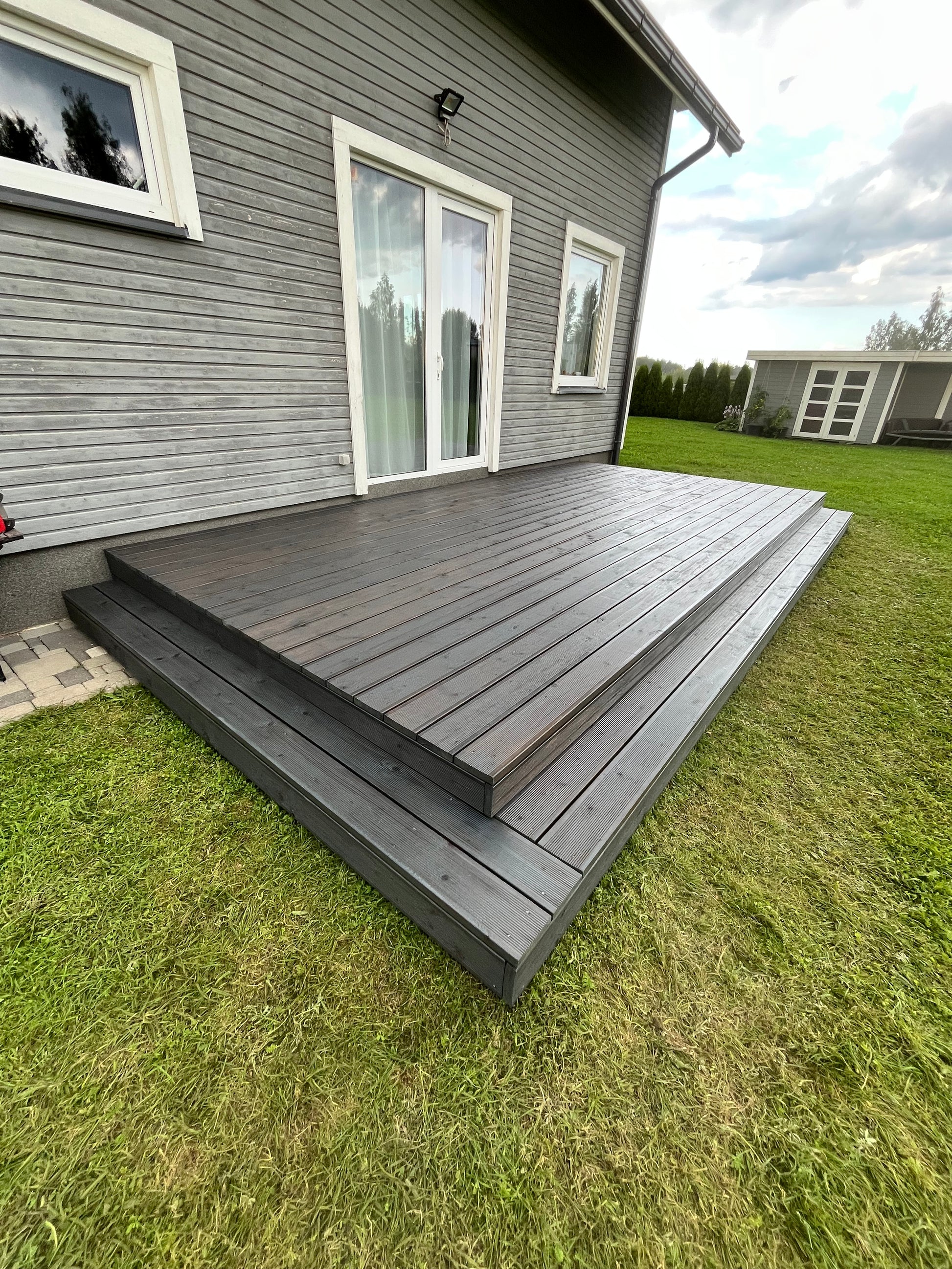 Wooden deck extension on a house with grass and sky in the background