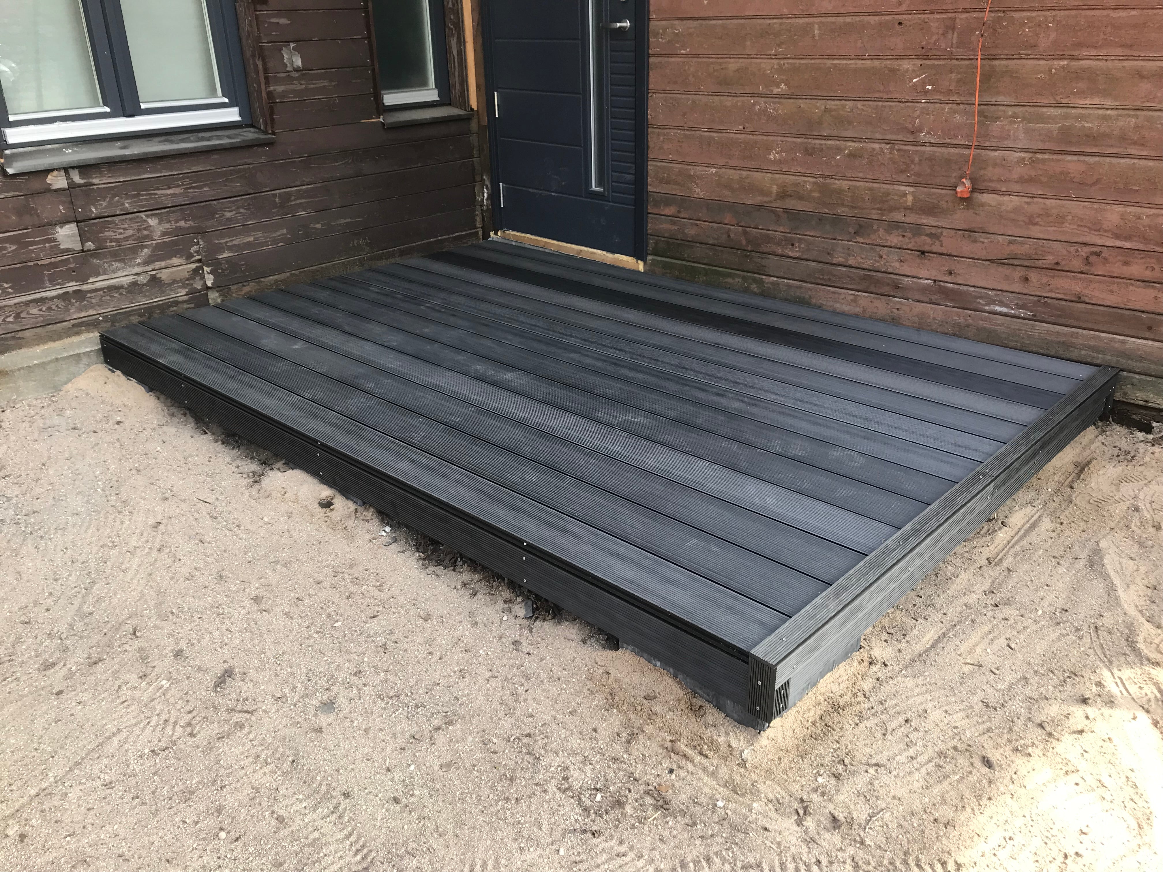 Gray wooden deck in front of a wooden house