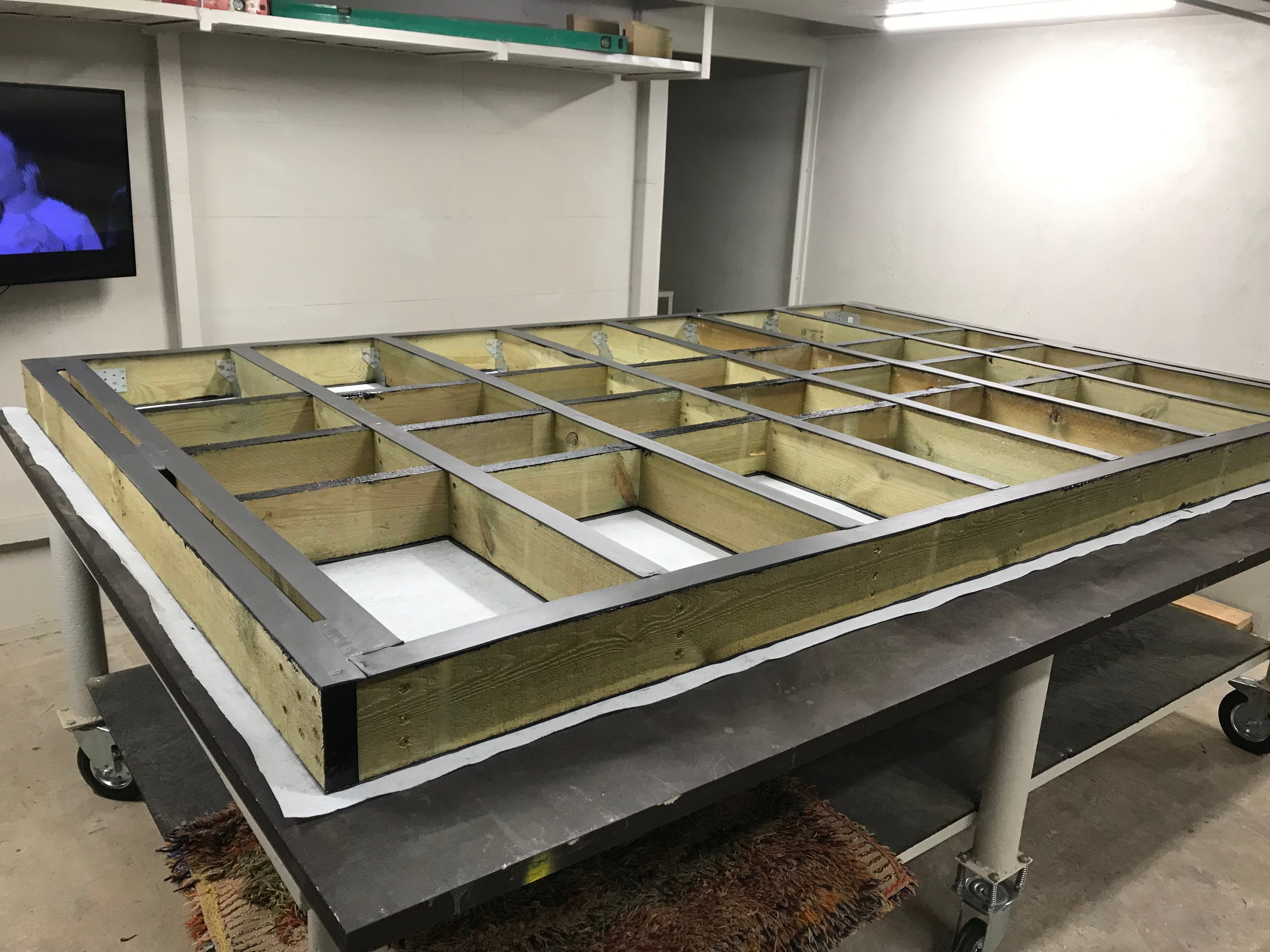 Wooden floor frame on a metal table in a workshop setting