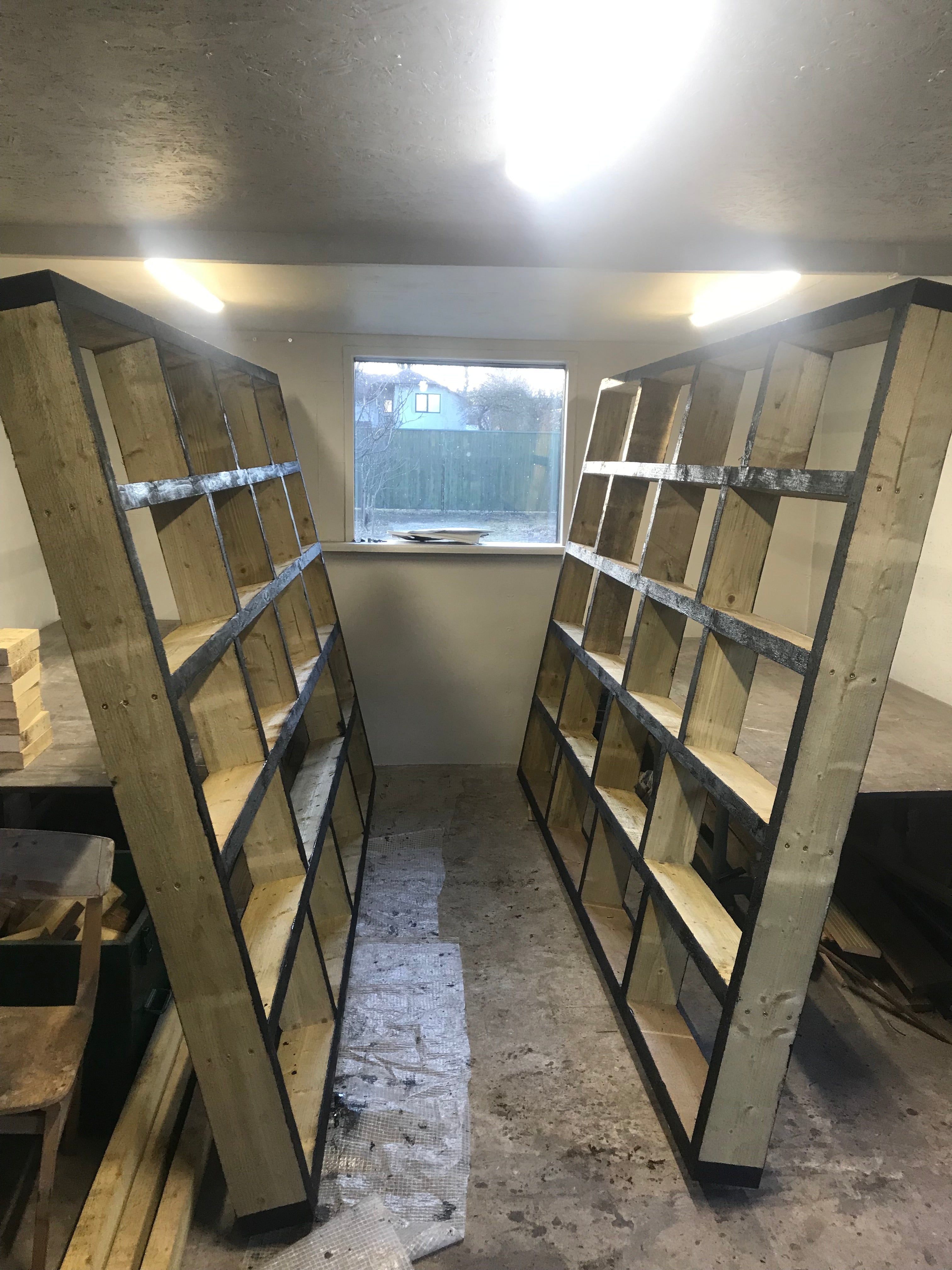 Wooden shelves against a concrete wall with a window in the background