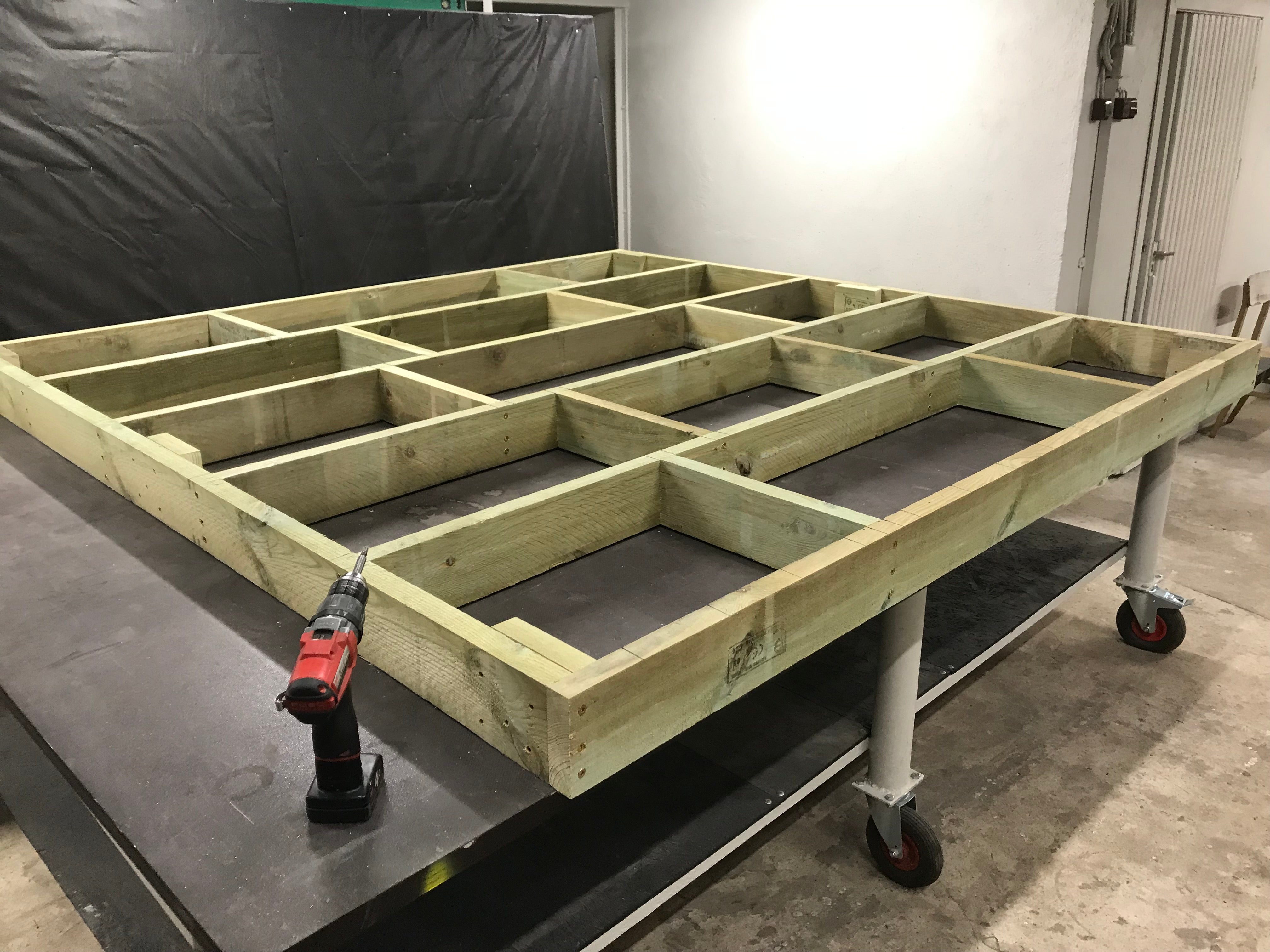 Wooden frame structure on a cart with tools in a workshop setting