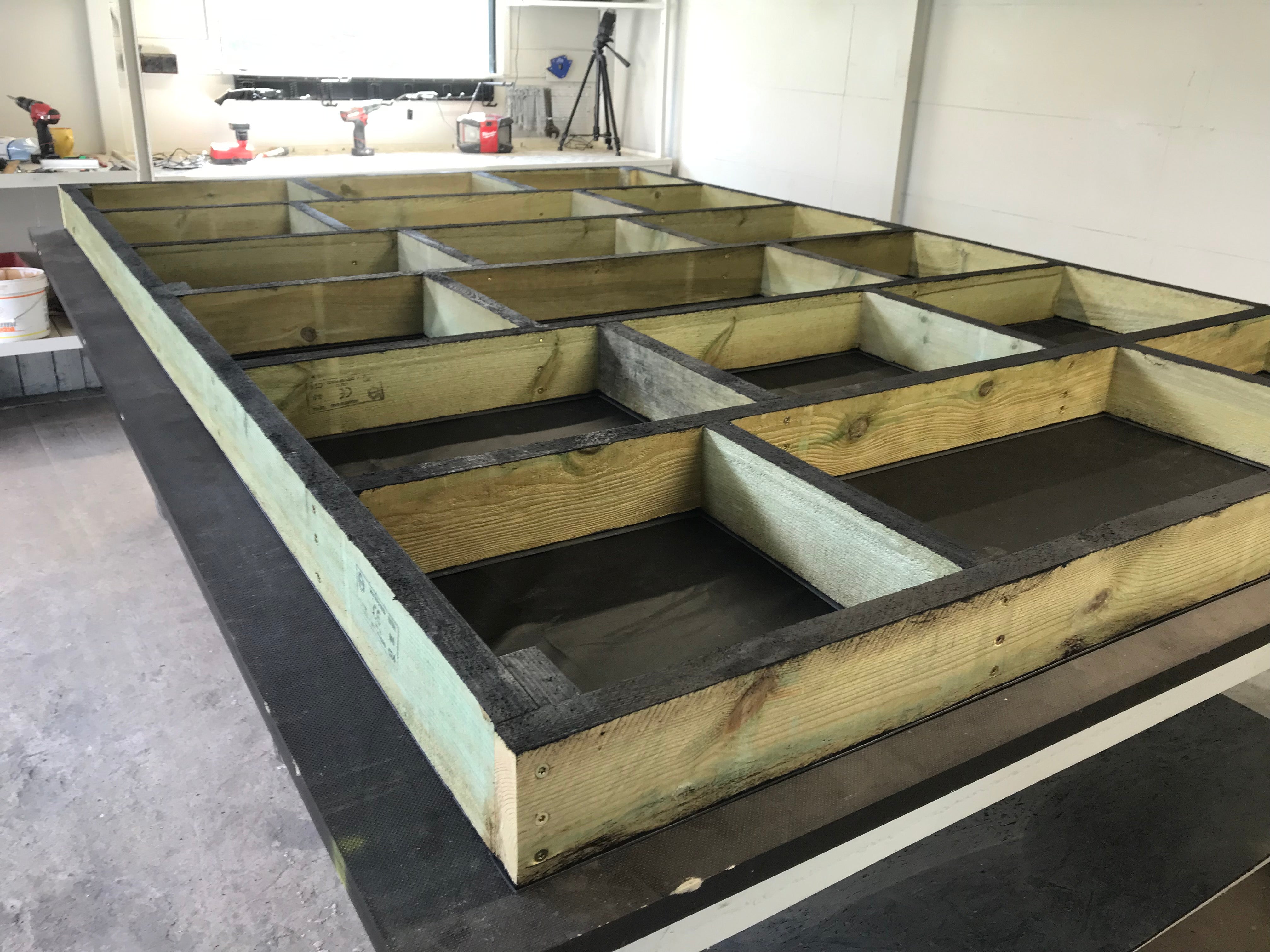 Wooden floor structure with concrete base in a workshop setting