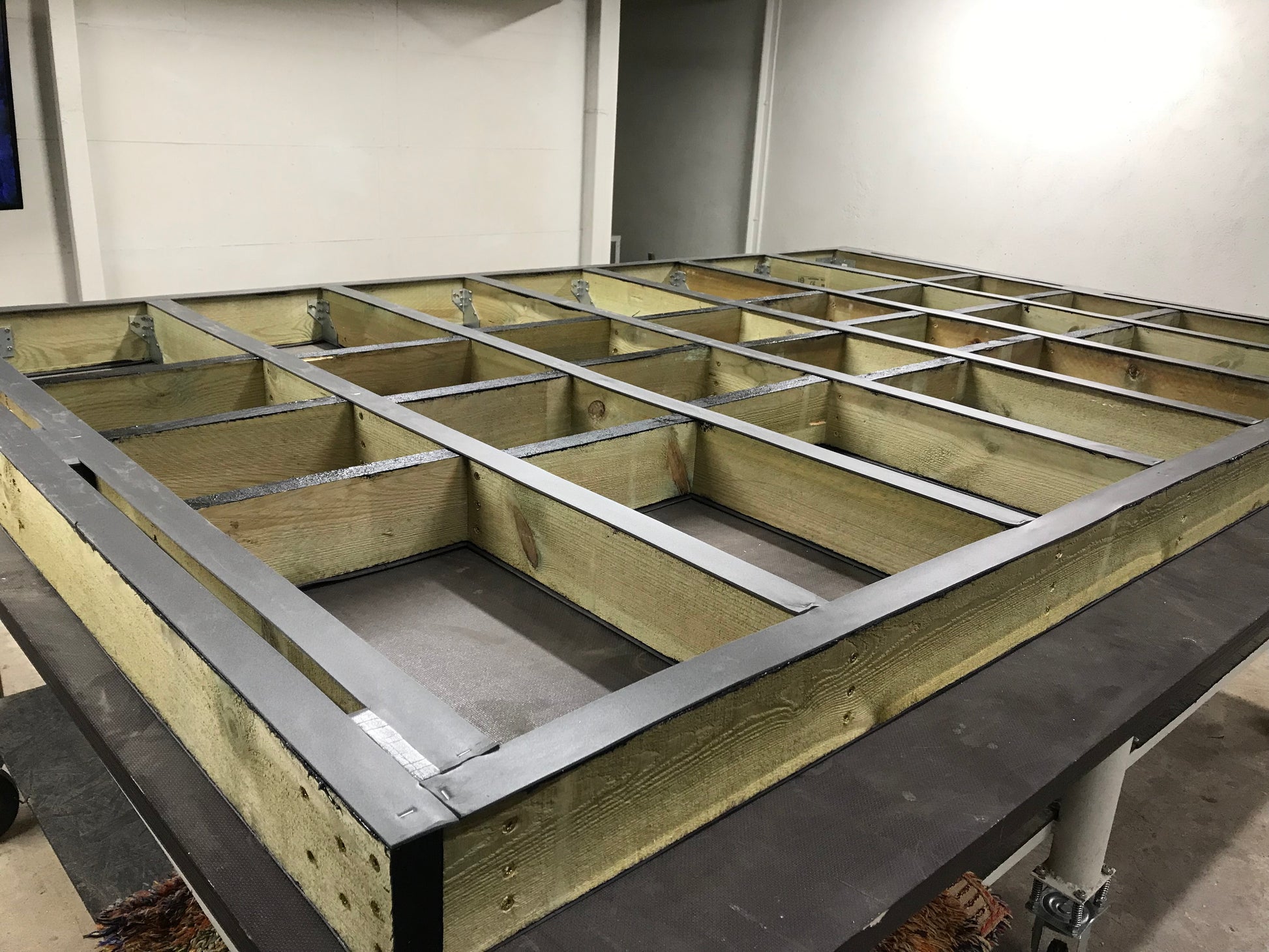 Wooden floor frame with metal beams on a concrete floor