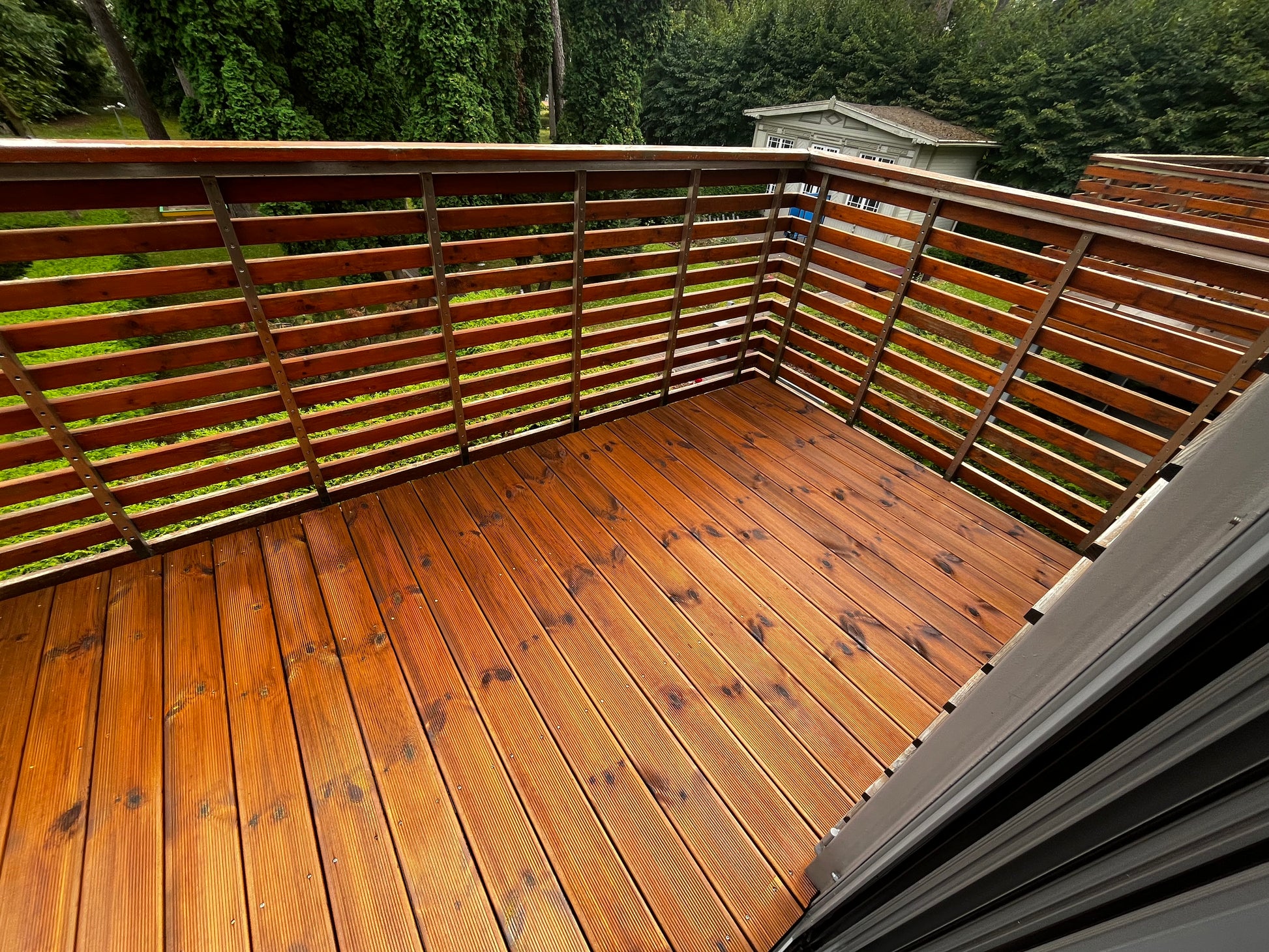 Wooden deck with railing and greenery in the background
