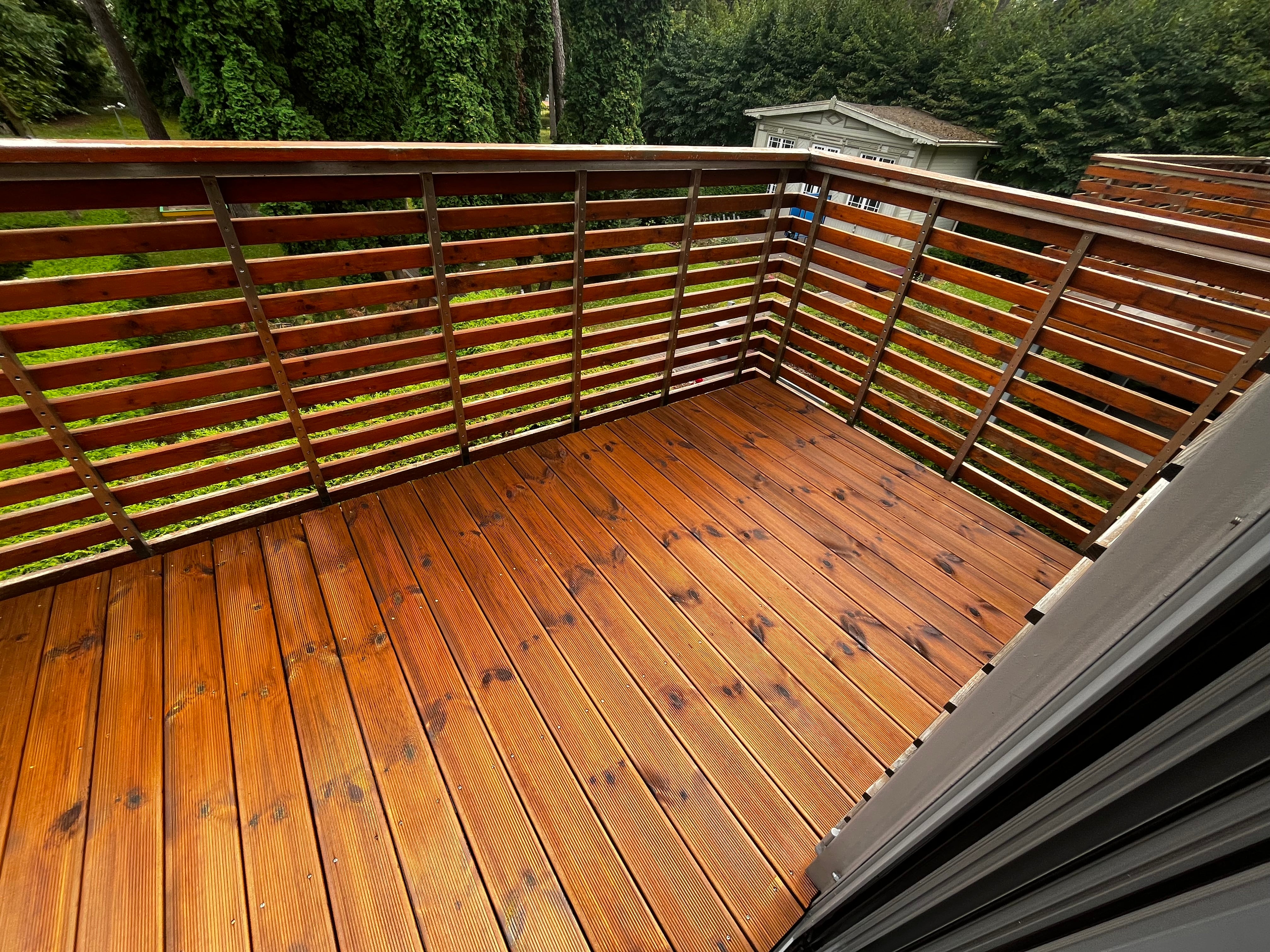Wooden deck with railing and greenery in the background