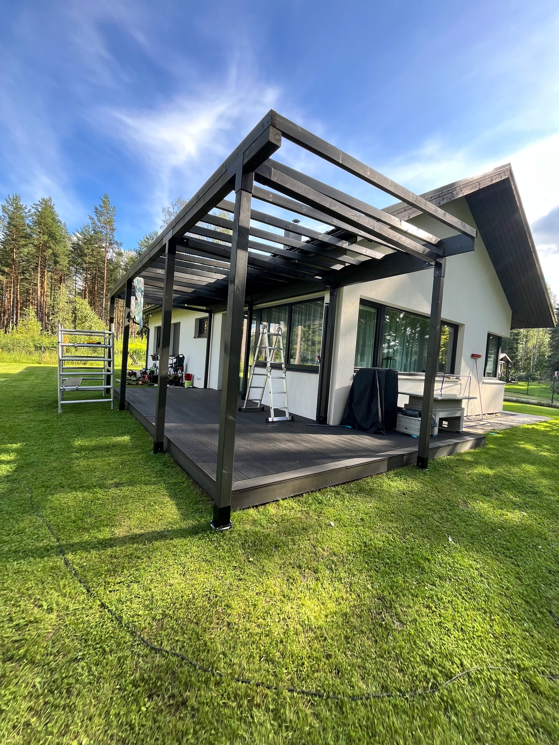 Modern house with a large outdoor deck with pergola and grassy area