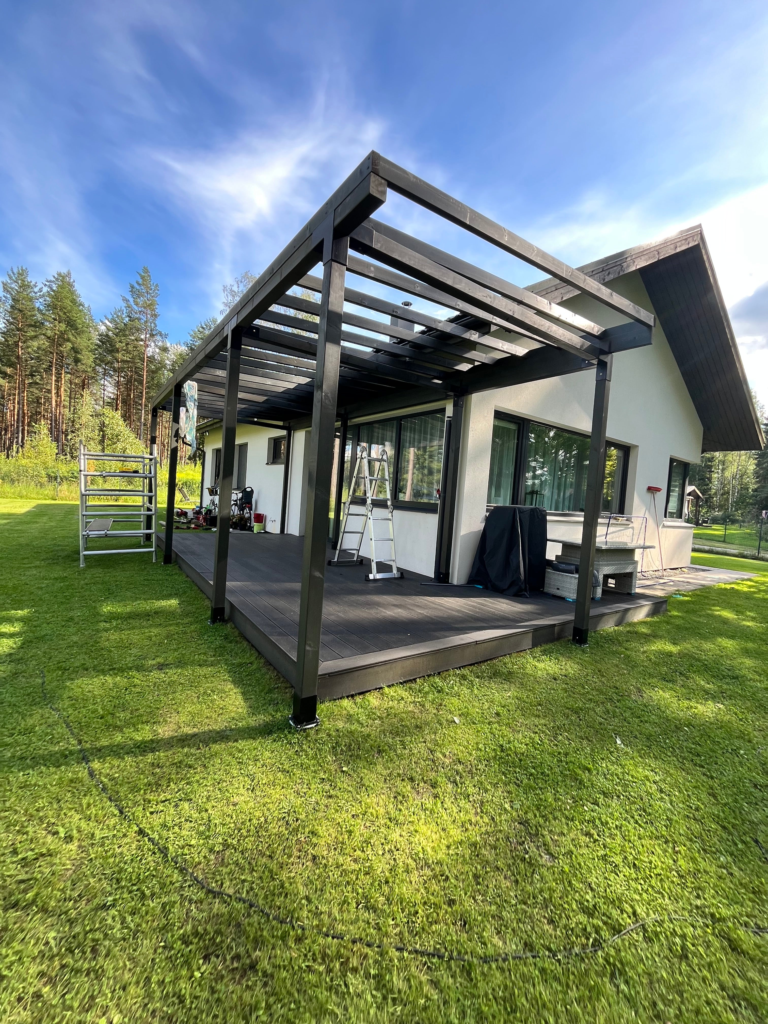 Modern house with a large outdoor deck with pergola and grassy area