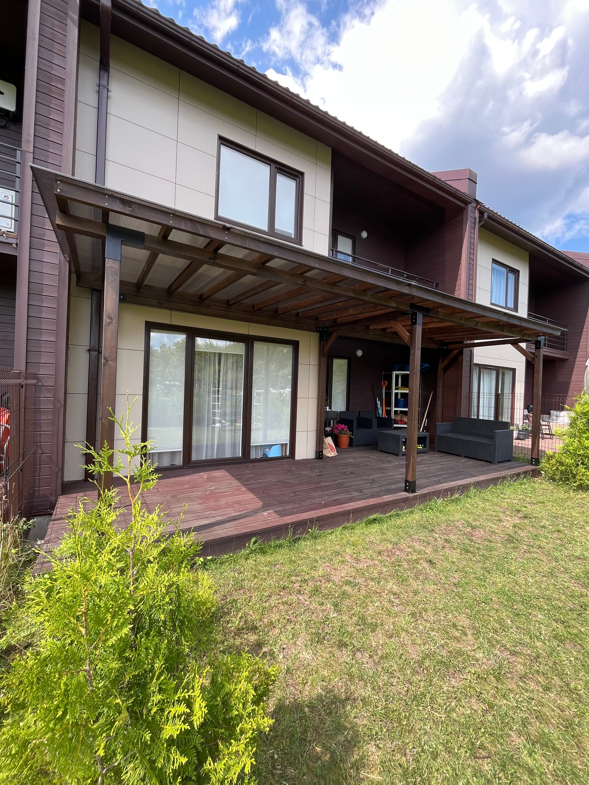 Two-story house with a deck and outdoor furniture on a grassy area