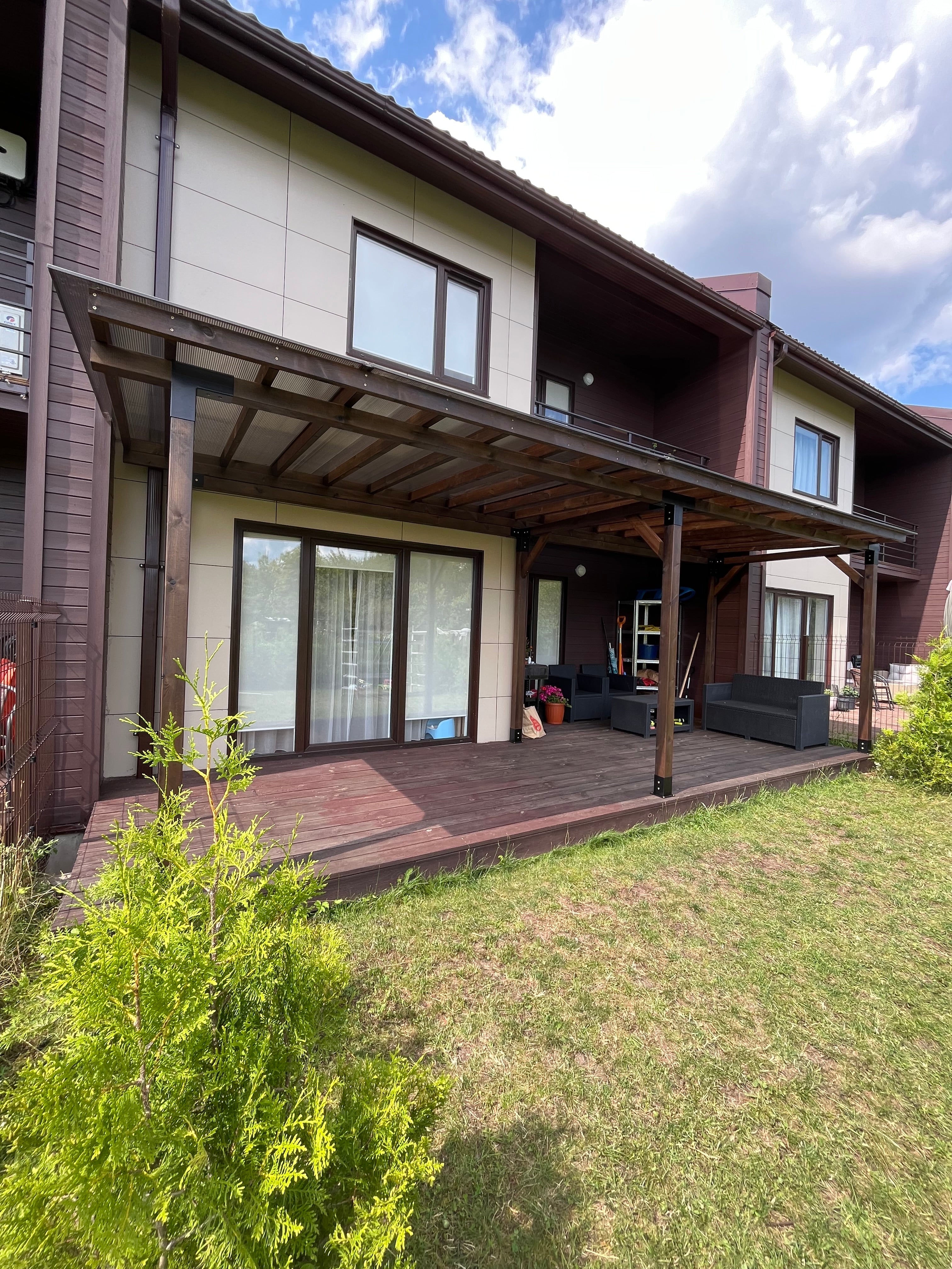 Two-story house with a deck and outdoor furniture on a grassy area