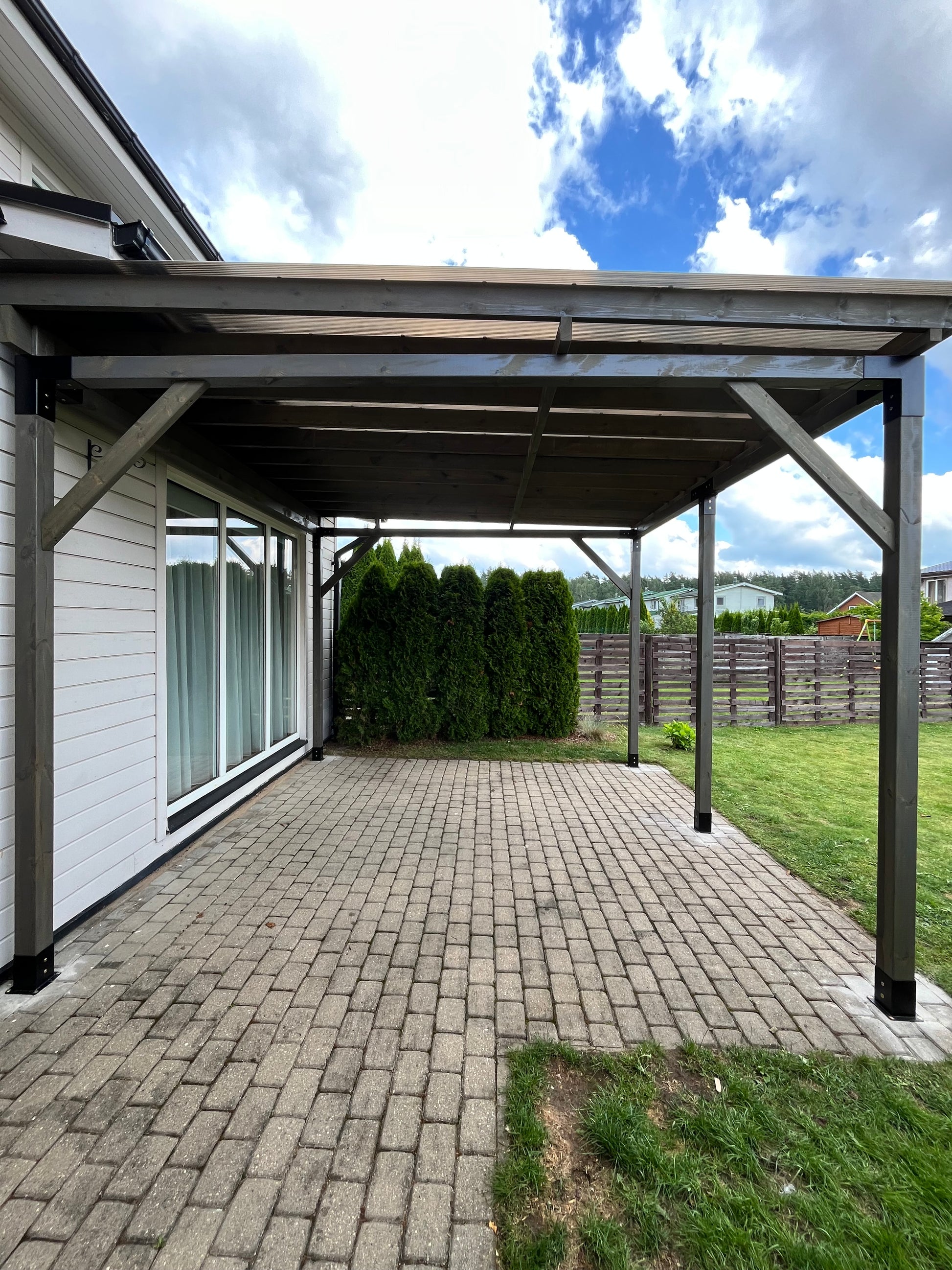 Outdoor patio area with a glass-enclosed pergola on a sunny day.