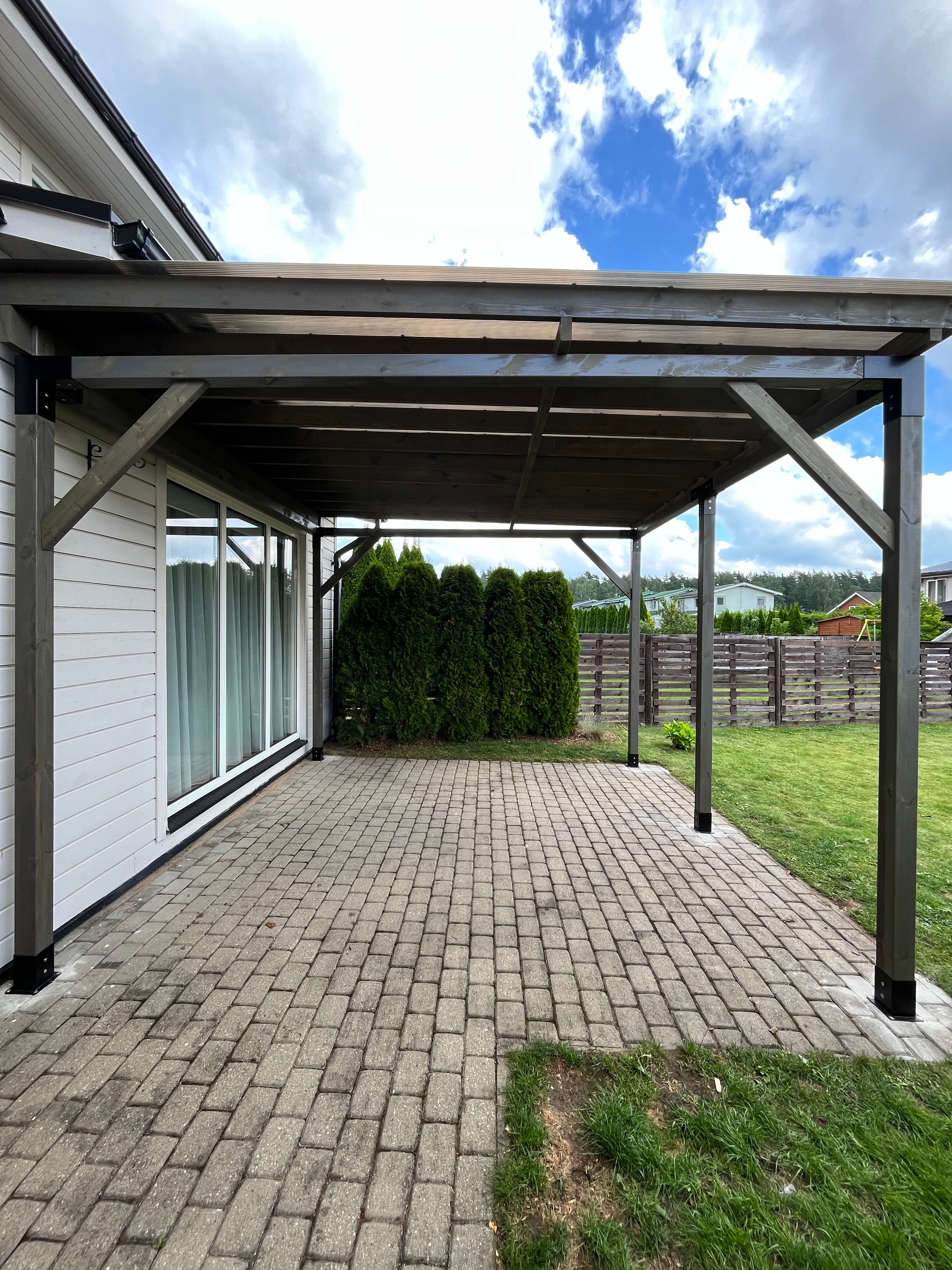 Outdoor patio area with a glass-enclosed pergola on a sunny day.