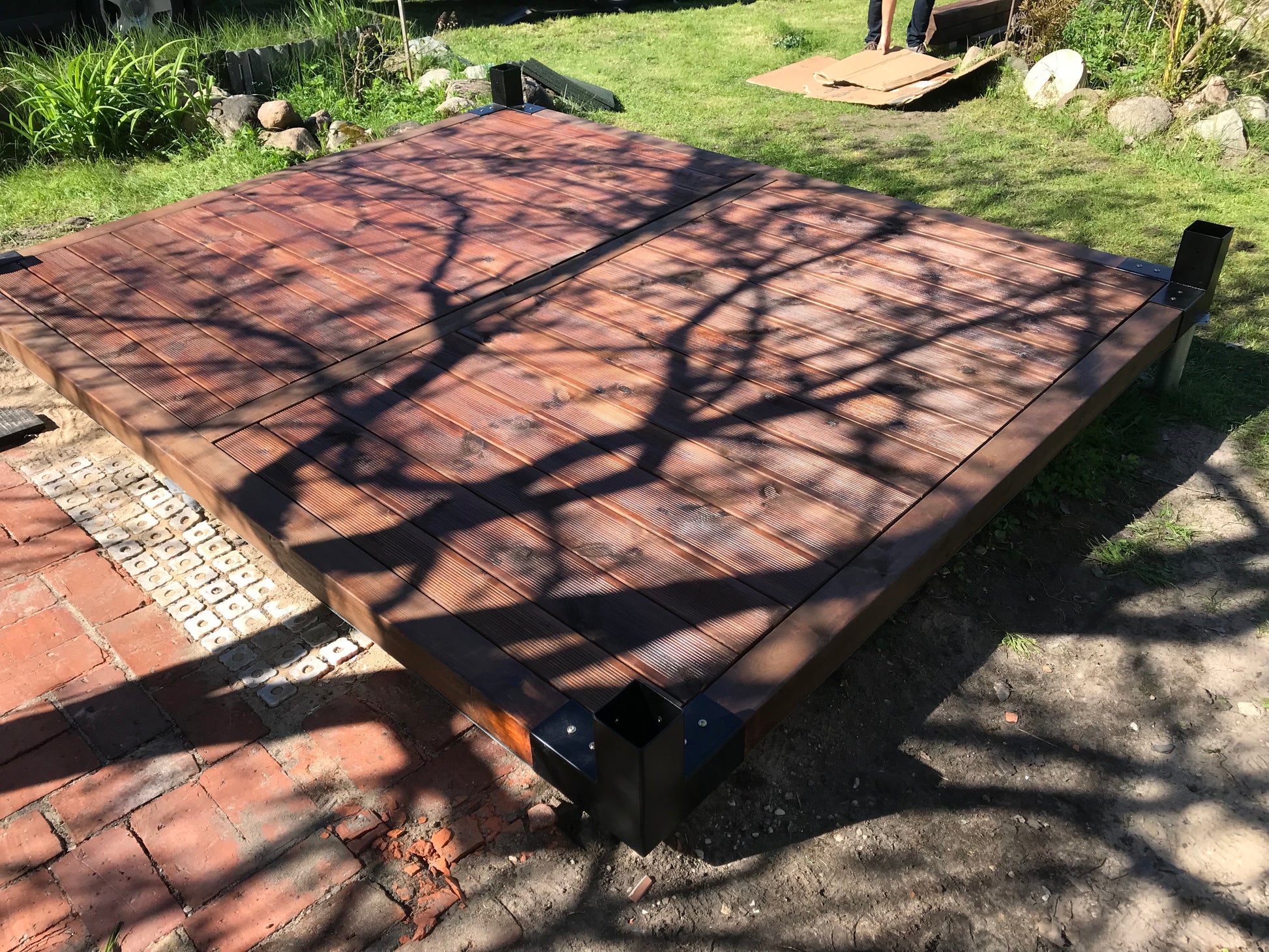 Wooden platform with tree shadows on a grassy area
