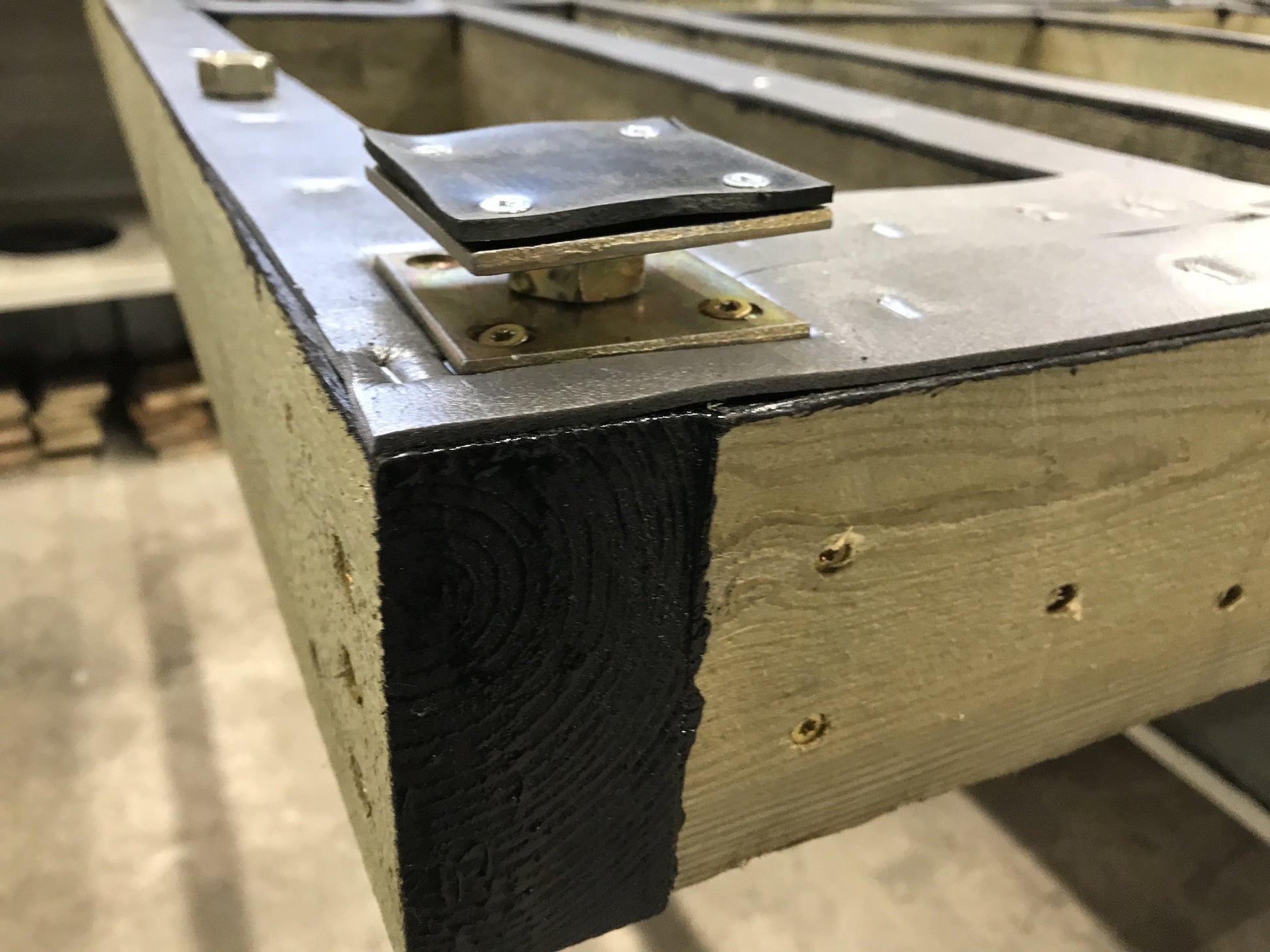 Close-up of a metal bracket attached to wooden and concrete structure