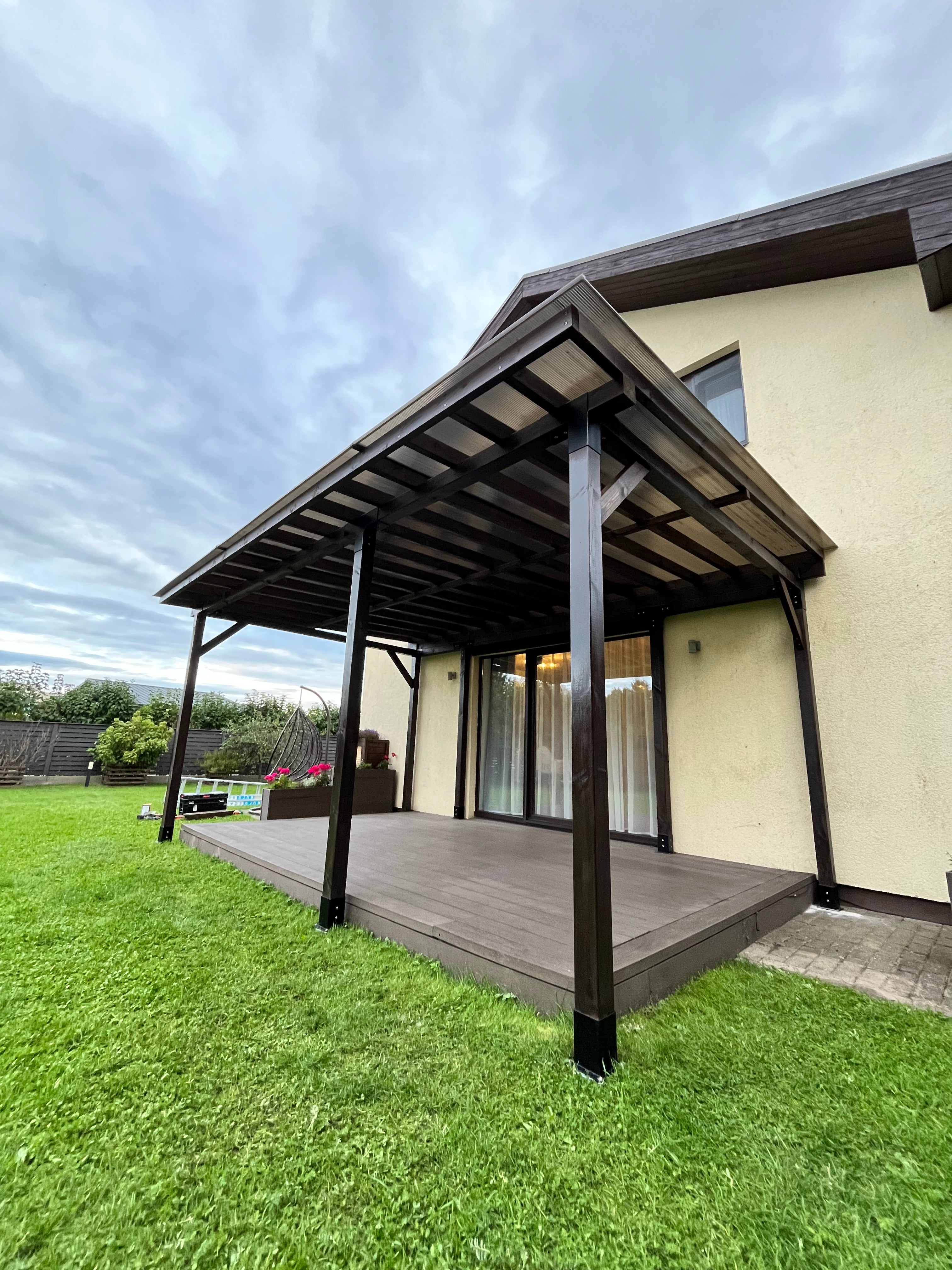 Wooden outdoor furniture set with chairs and table on a grassy area and pergola