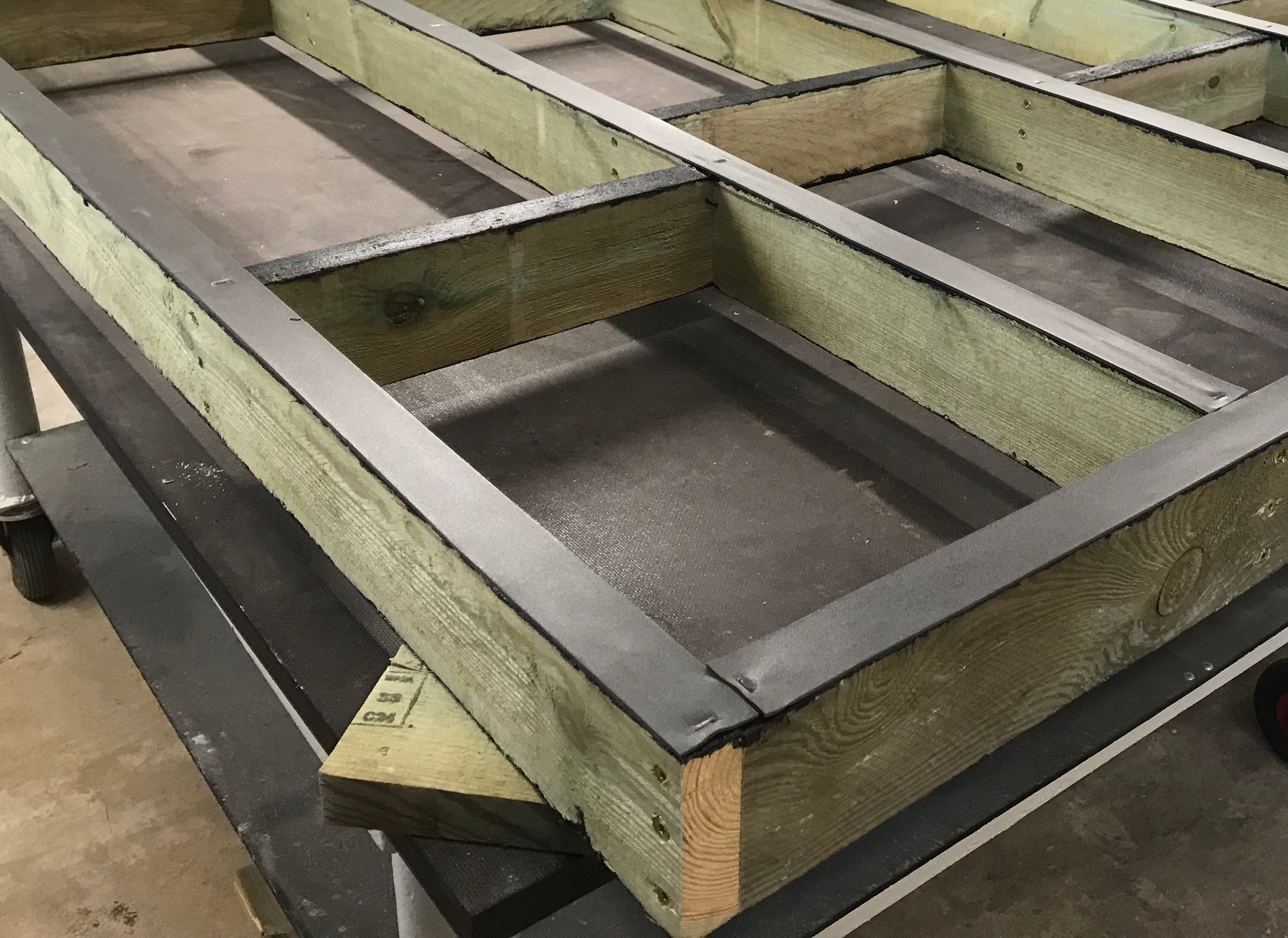 Wooden beams with metal brackets on a concrete floor