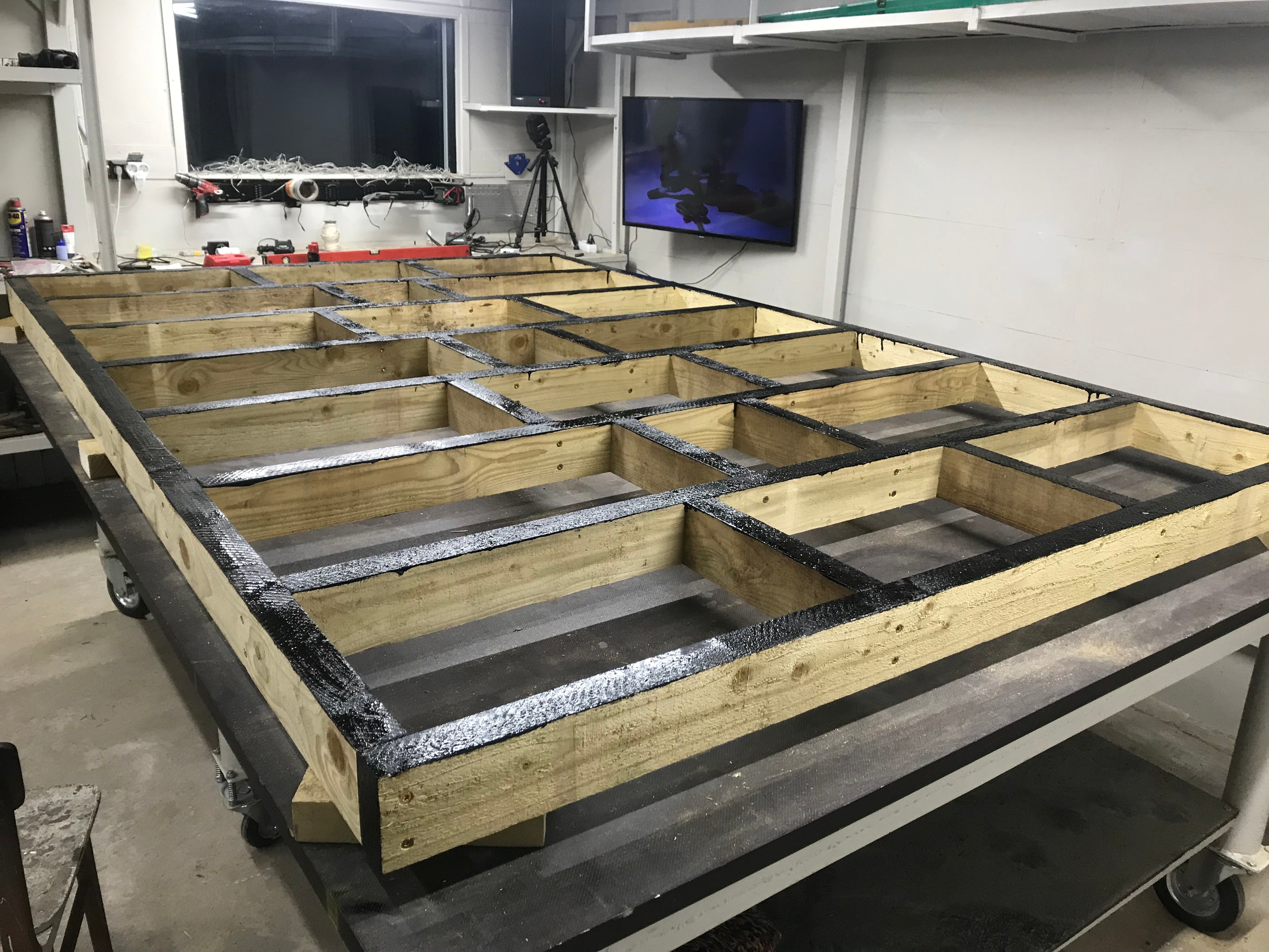 Wooden frames with black material on a workbench in a workshop setting.