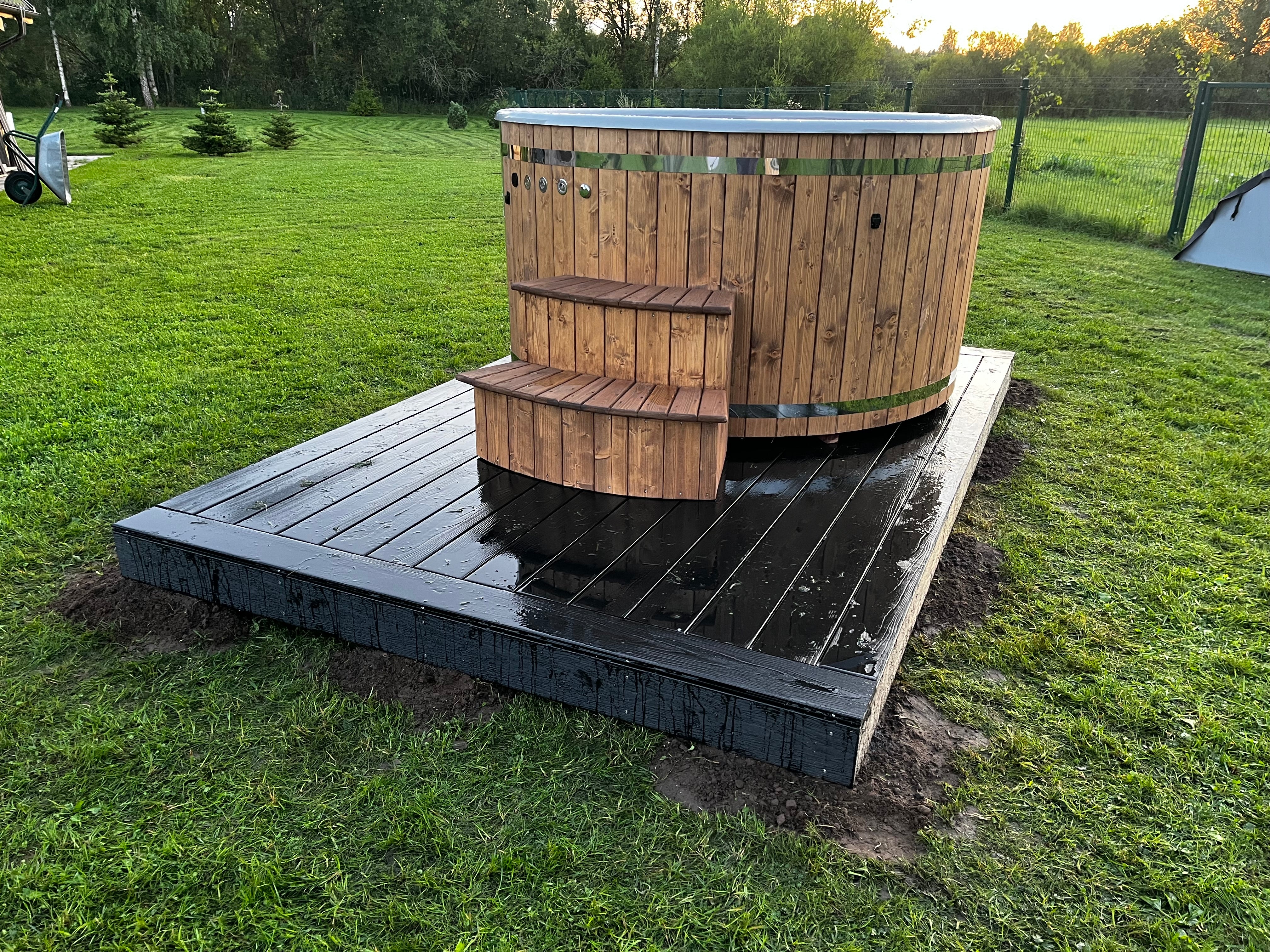 Wooden hot tub on a platform in a grassy outdoor area
