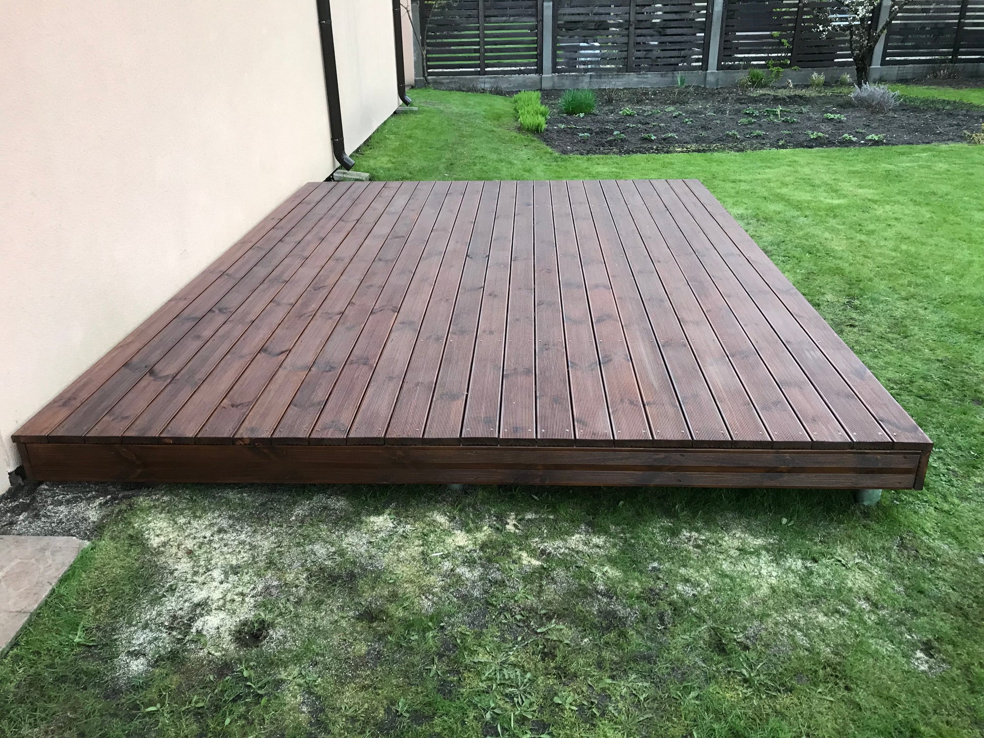 Wooden deck on a grassy area with a building in the background