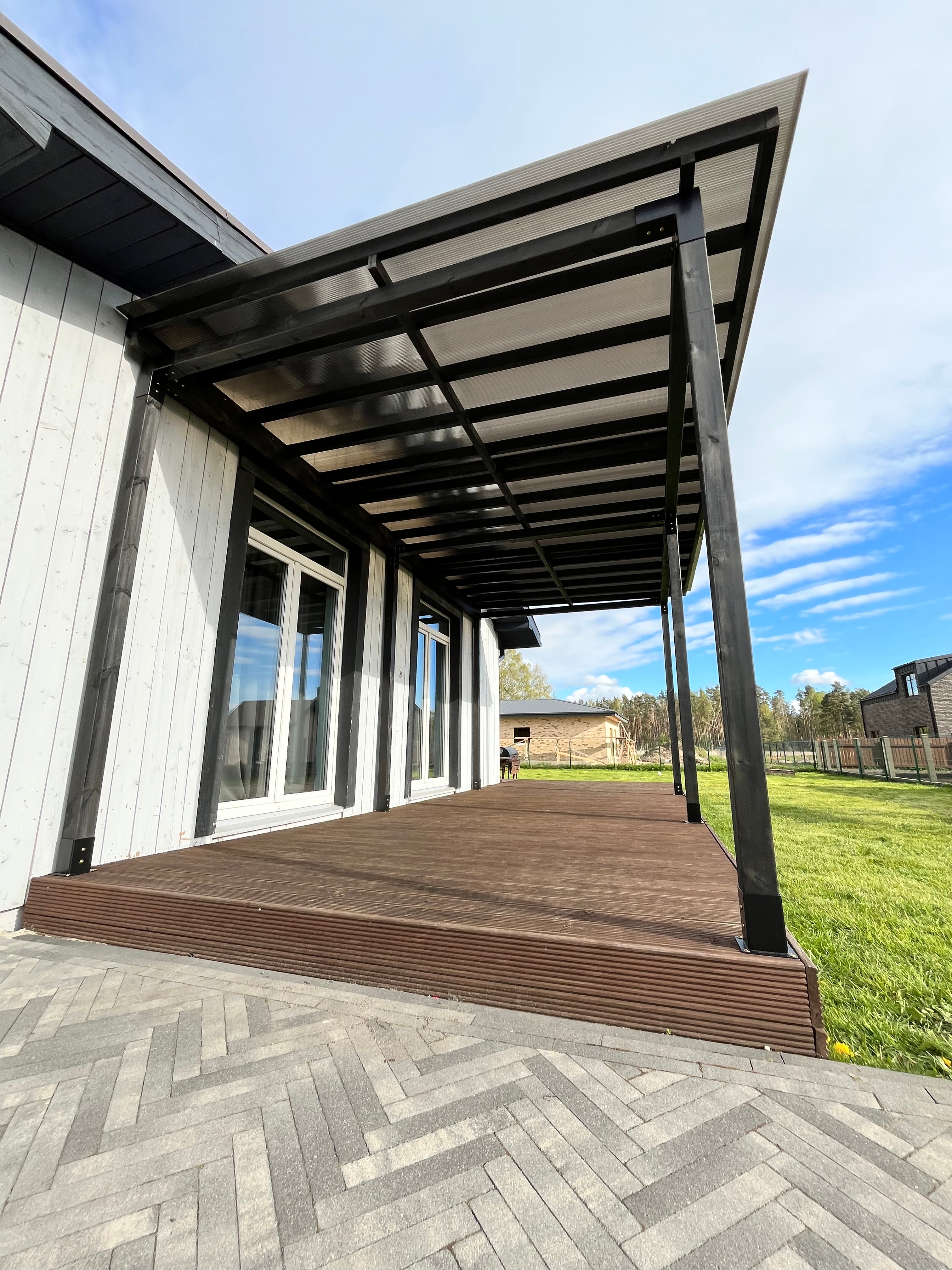 Modern outdoor deck with glass panels and wooden steps leading to a grassy area.