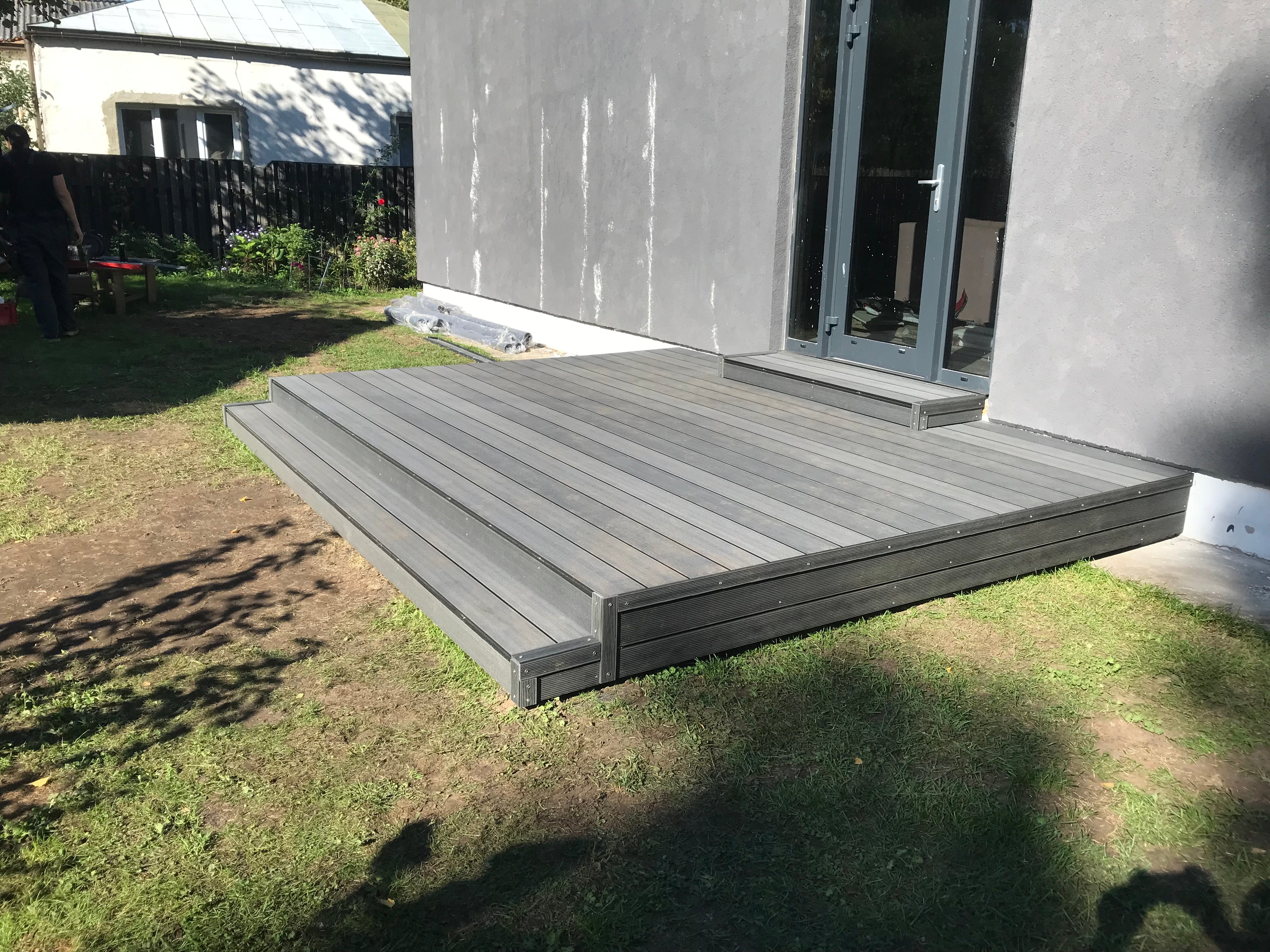 Gray wooden deck extending from a house onto a grassy area