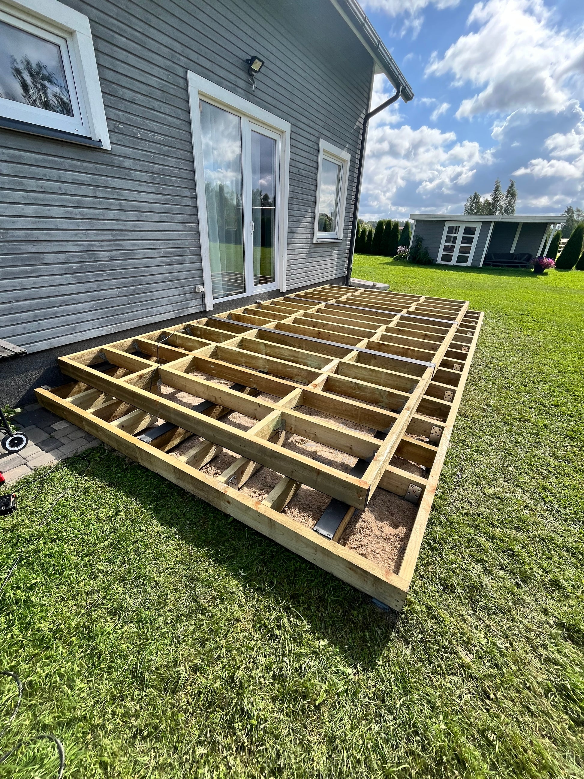 Wooden deck structure on a grassy area next to a house