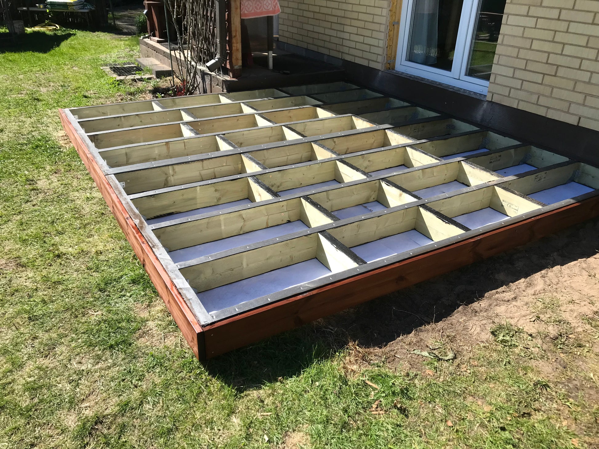 Wooden deck foundation with concrete base in a backyard setting