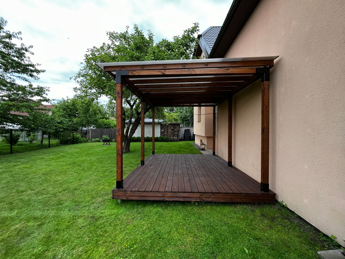Wooden pergola attached to a house with green grass and trees in the background