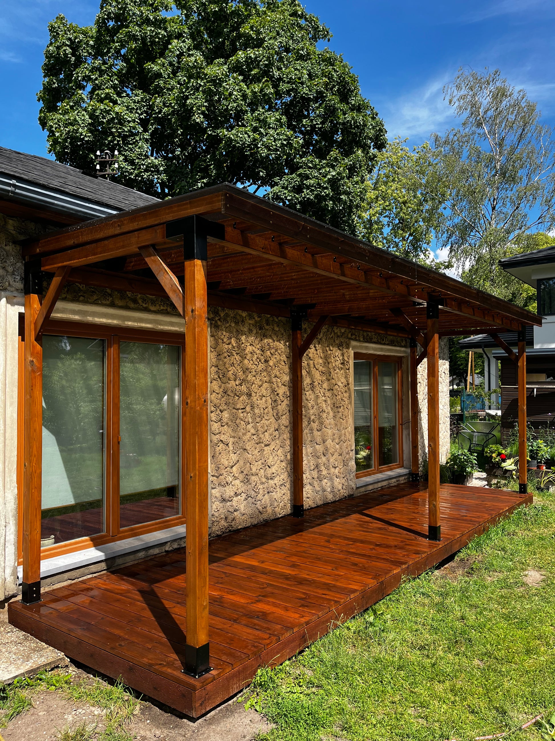 Wooden deck with glass panels and a bench, surrounded by greenery
