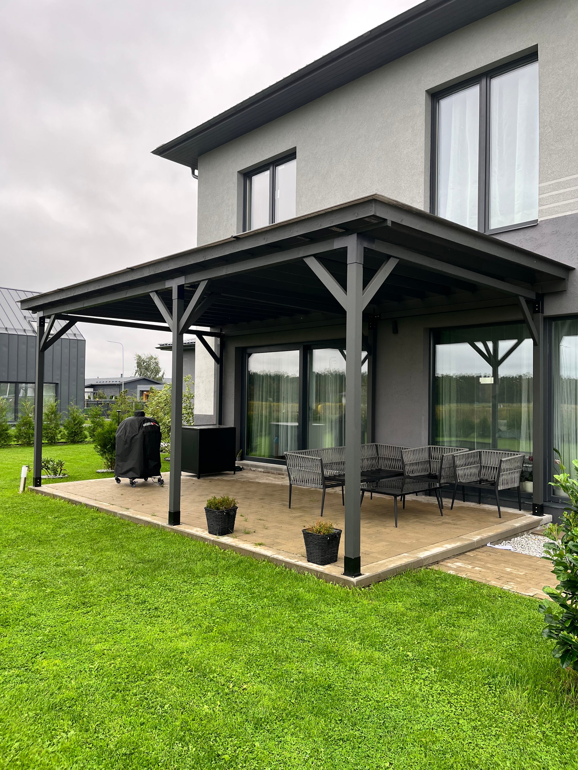Modern house with a covered patio area featuring outdoor furniture and plants.