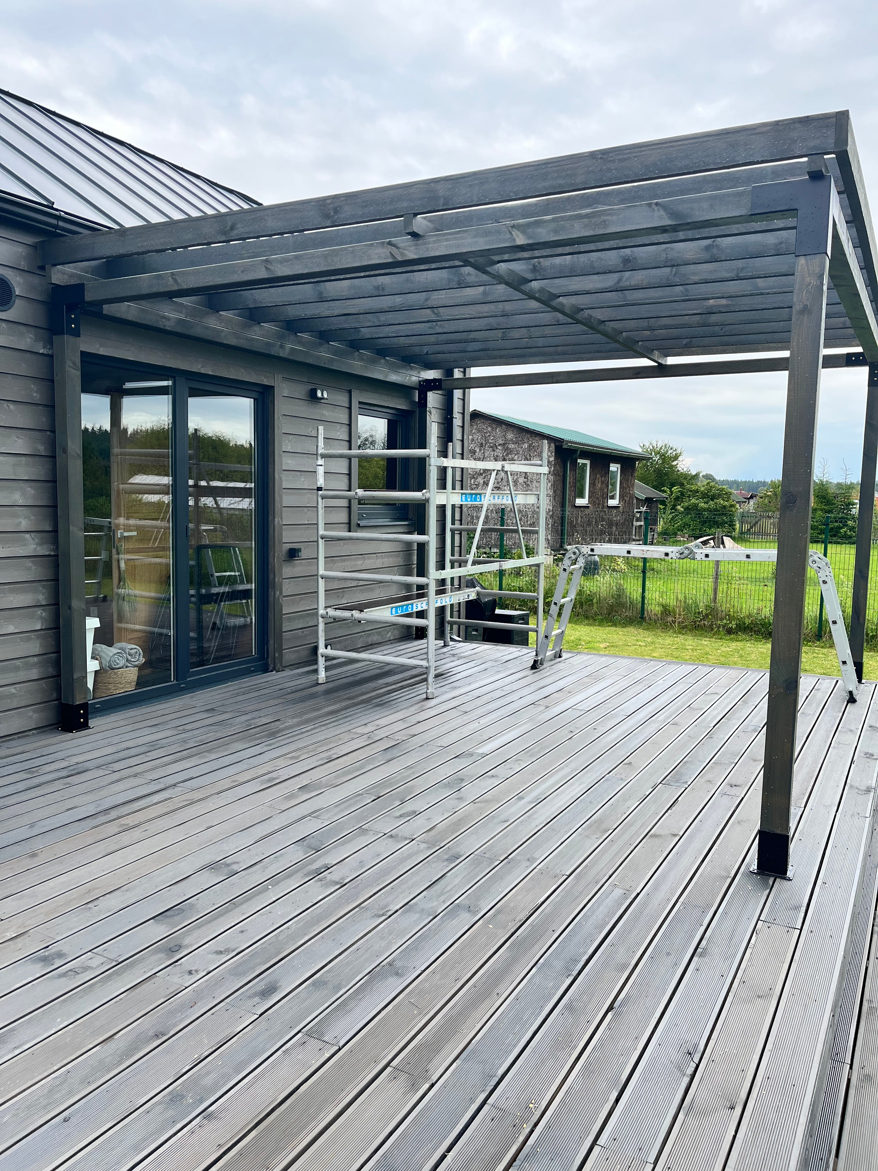Wooden deck with glass panels and metal railings on a cloudy day