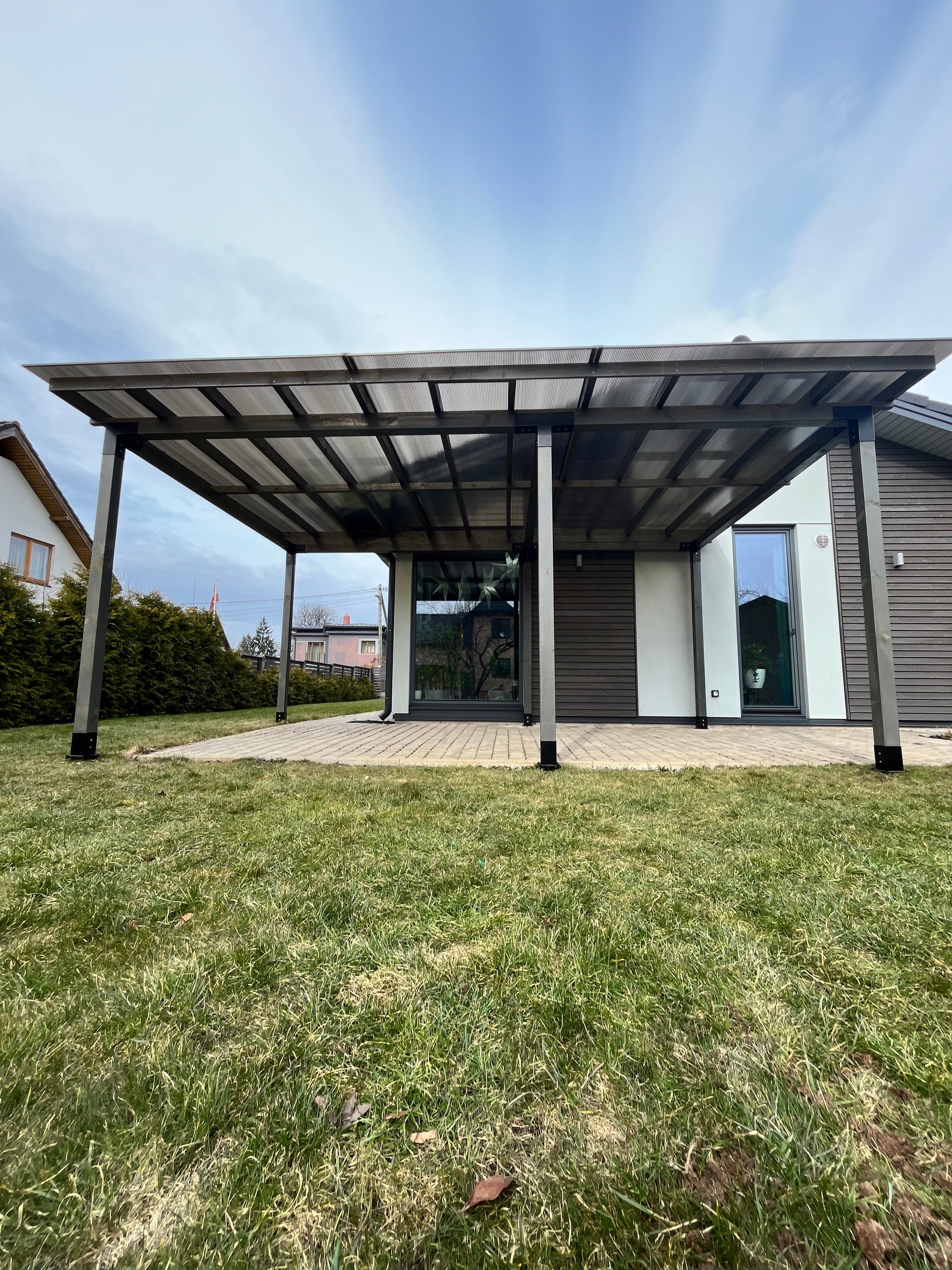 Patio cover attached to a house with grass and sky in the background
