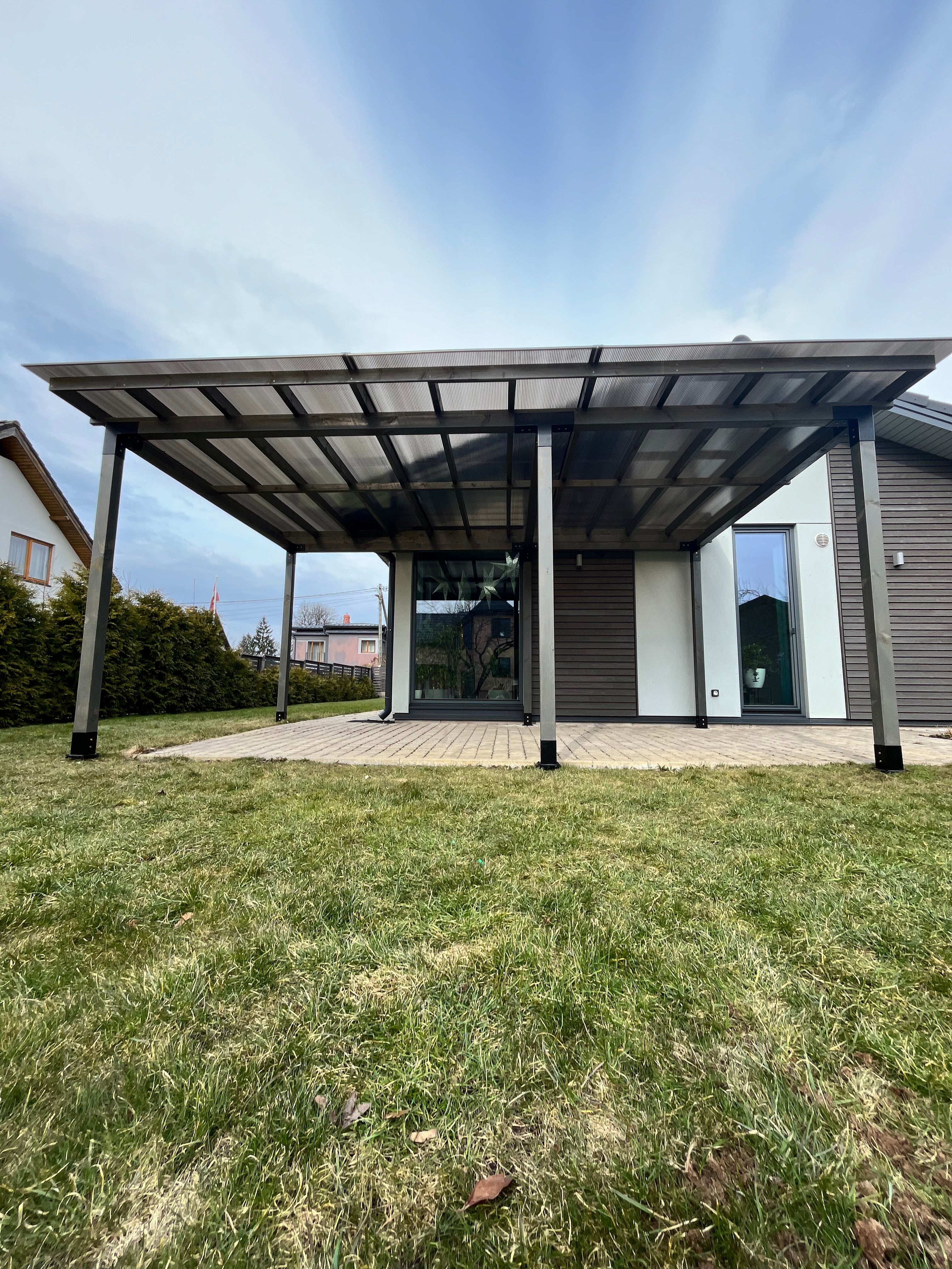 Patio cover attached to a house with grass and sky in the background