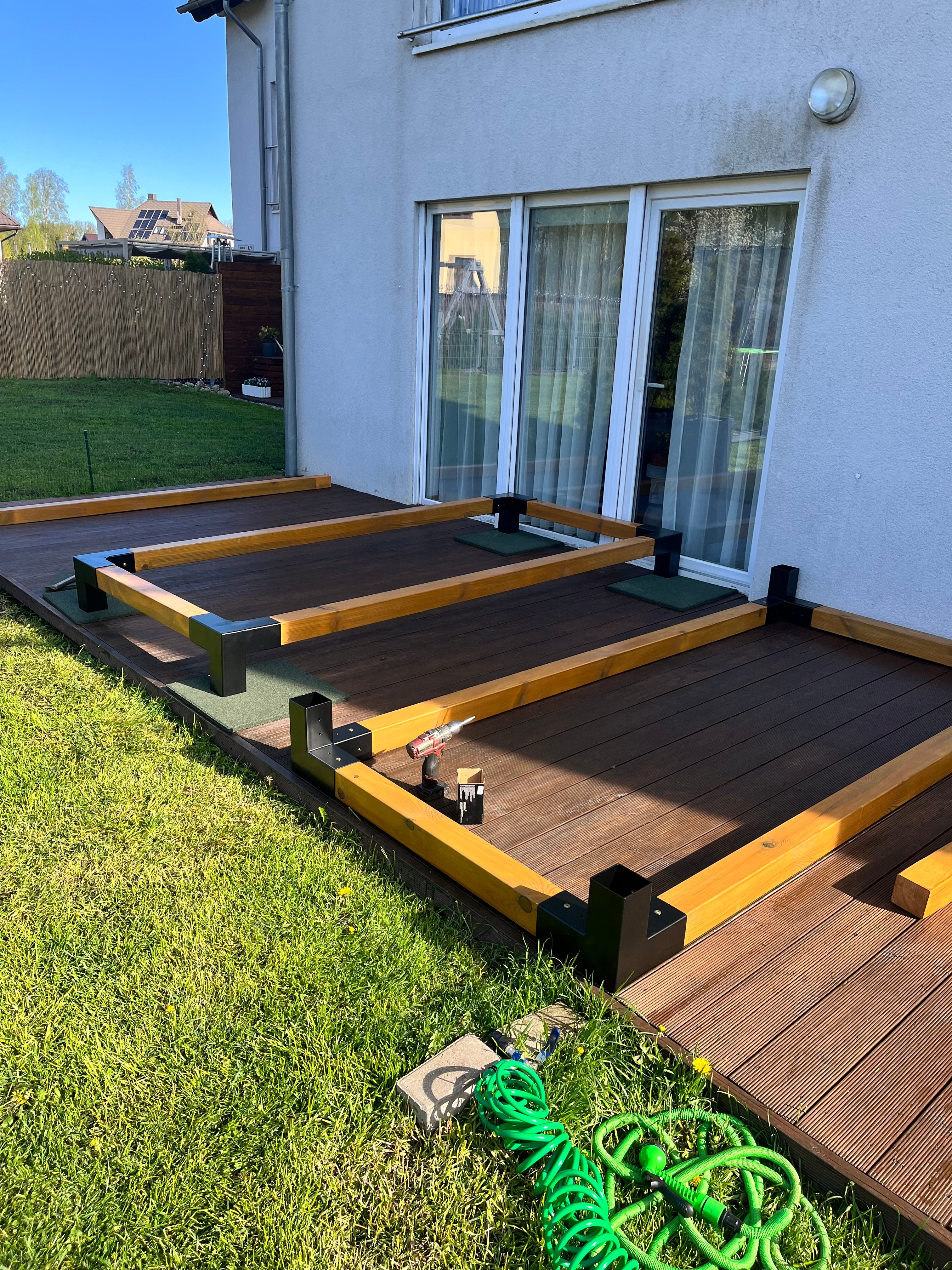 Wooden deck with yellow railings on a grassy area, with a house in the background.