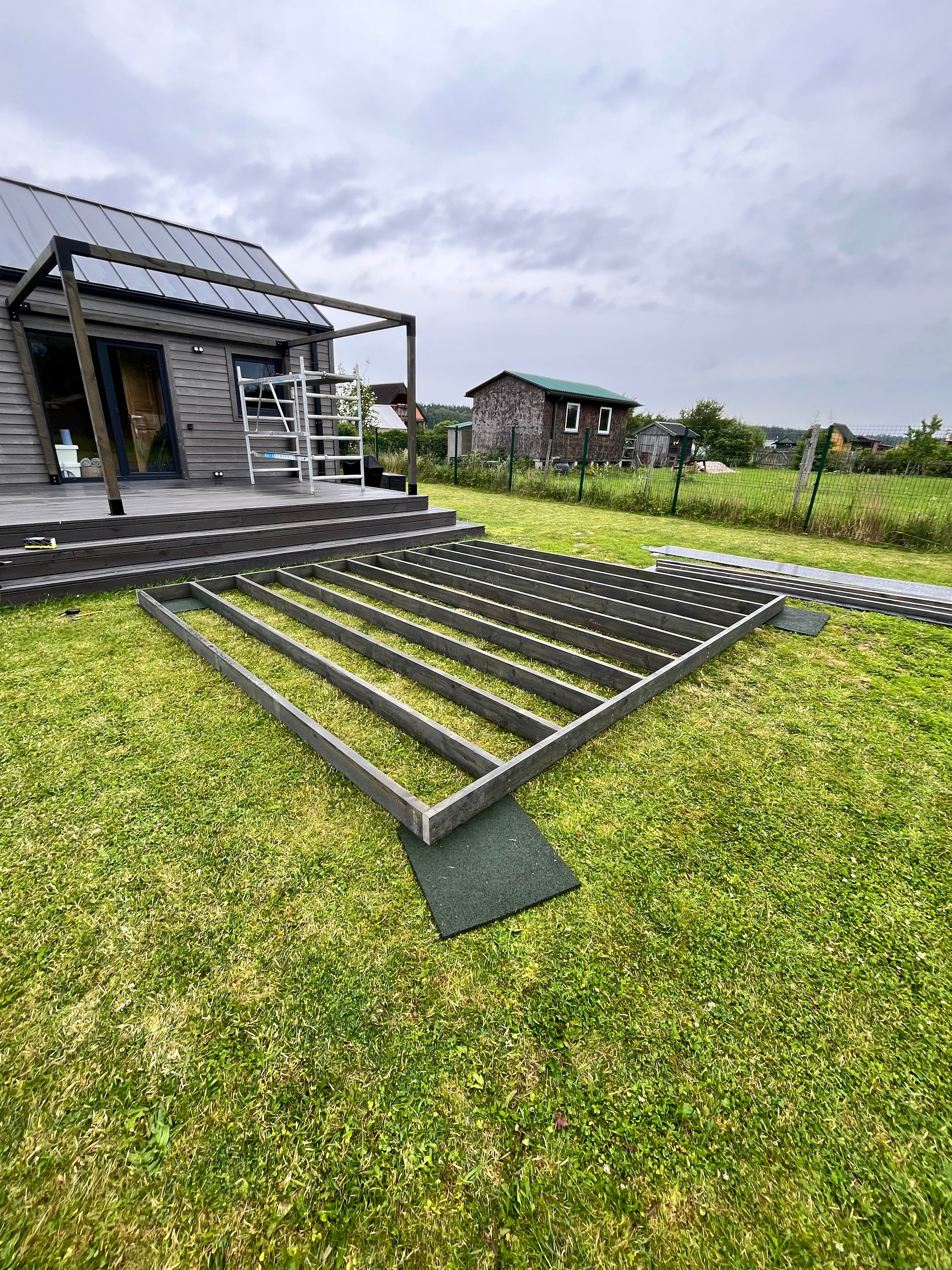 Metal staircase leading up to a house with a cloudy sky and grassy area.