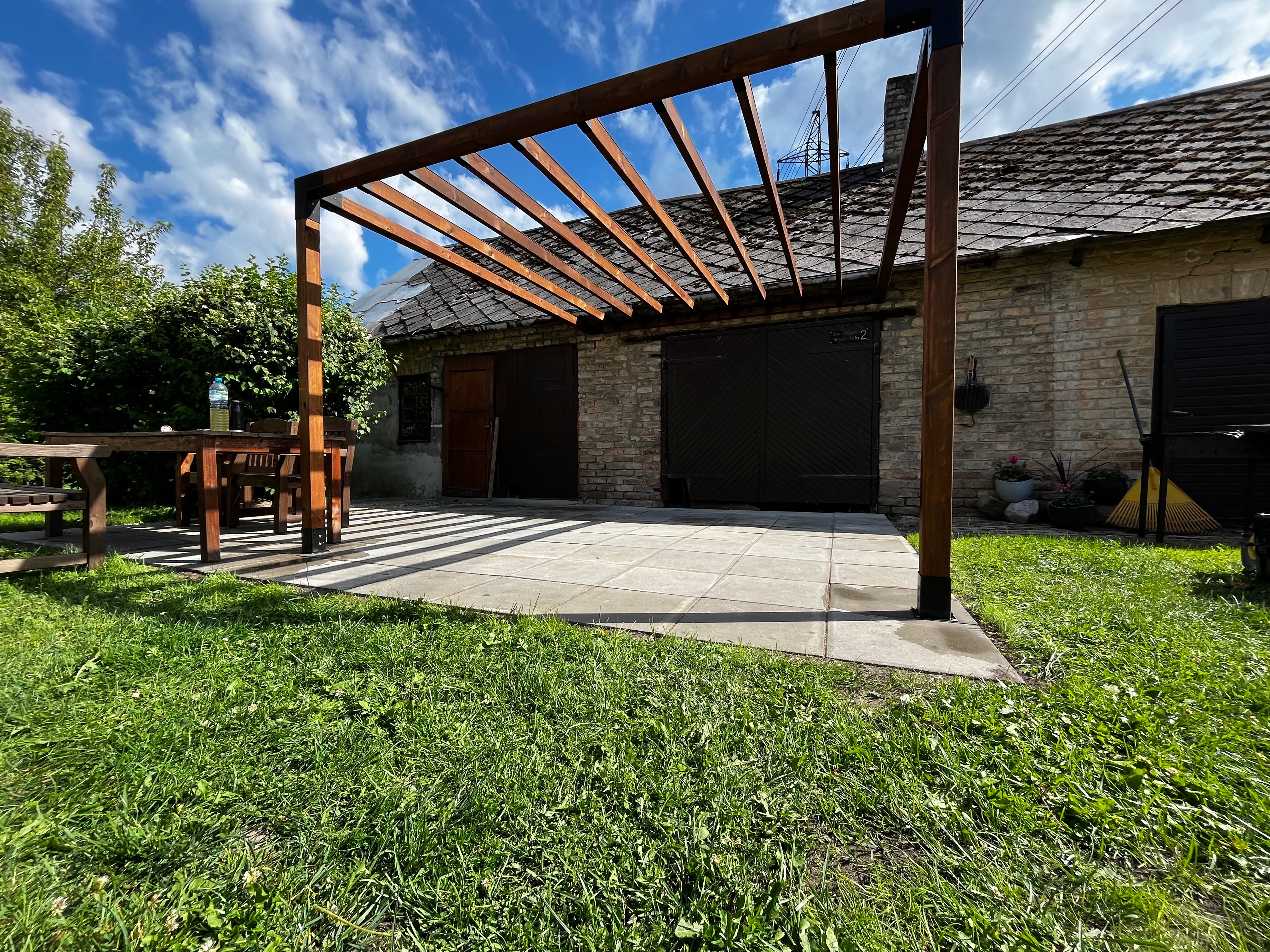 Wooden pergola in a backyard with grass and a clear sky
