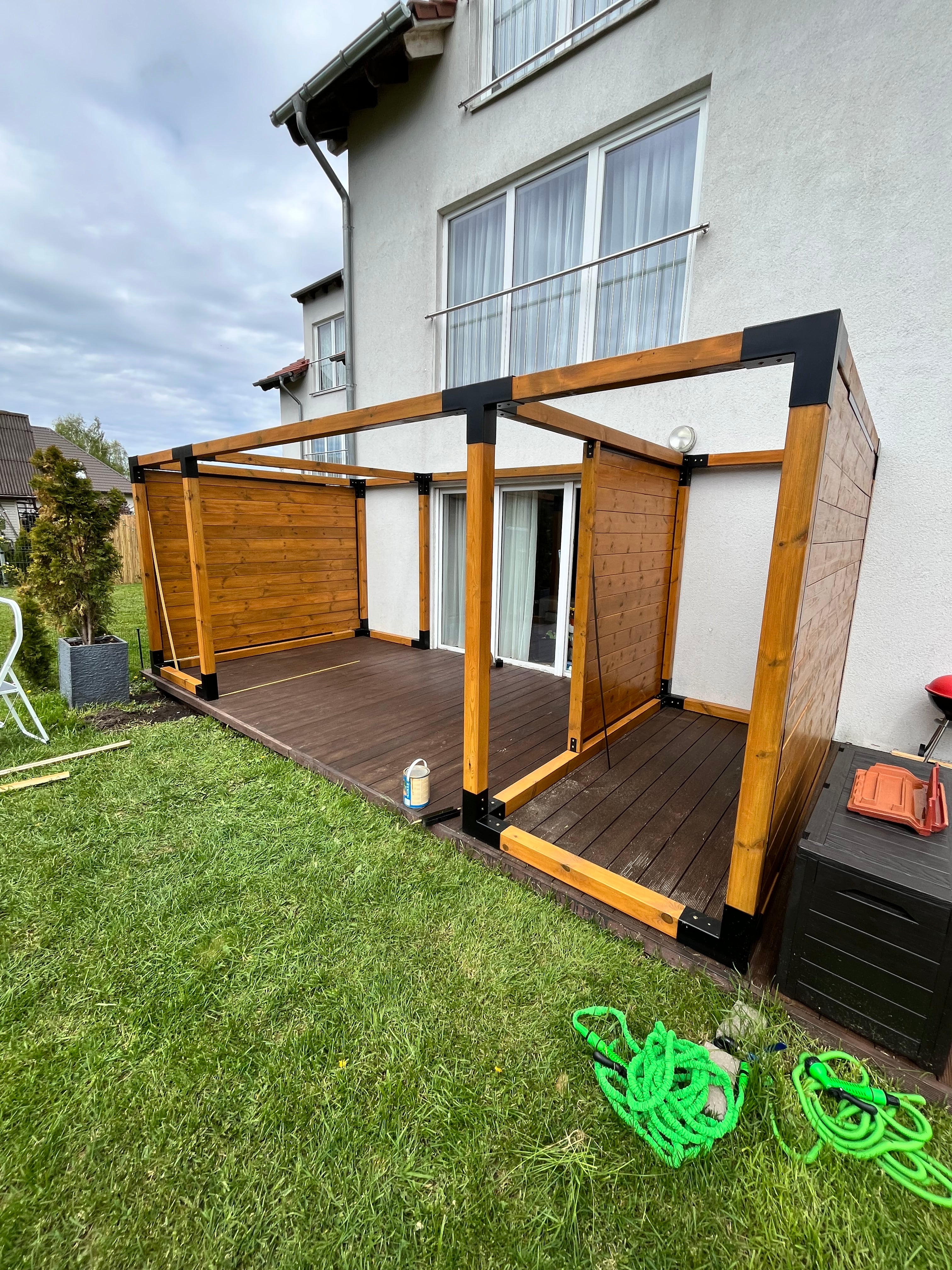 Wooden shelf with black accents on a grassy area outside a house