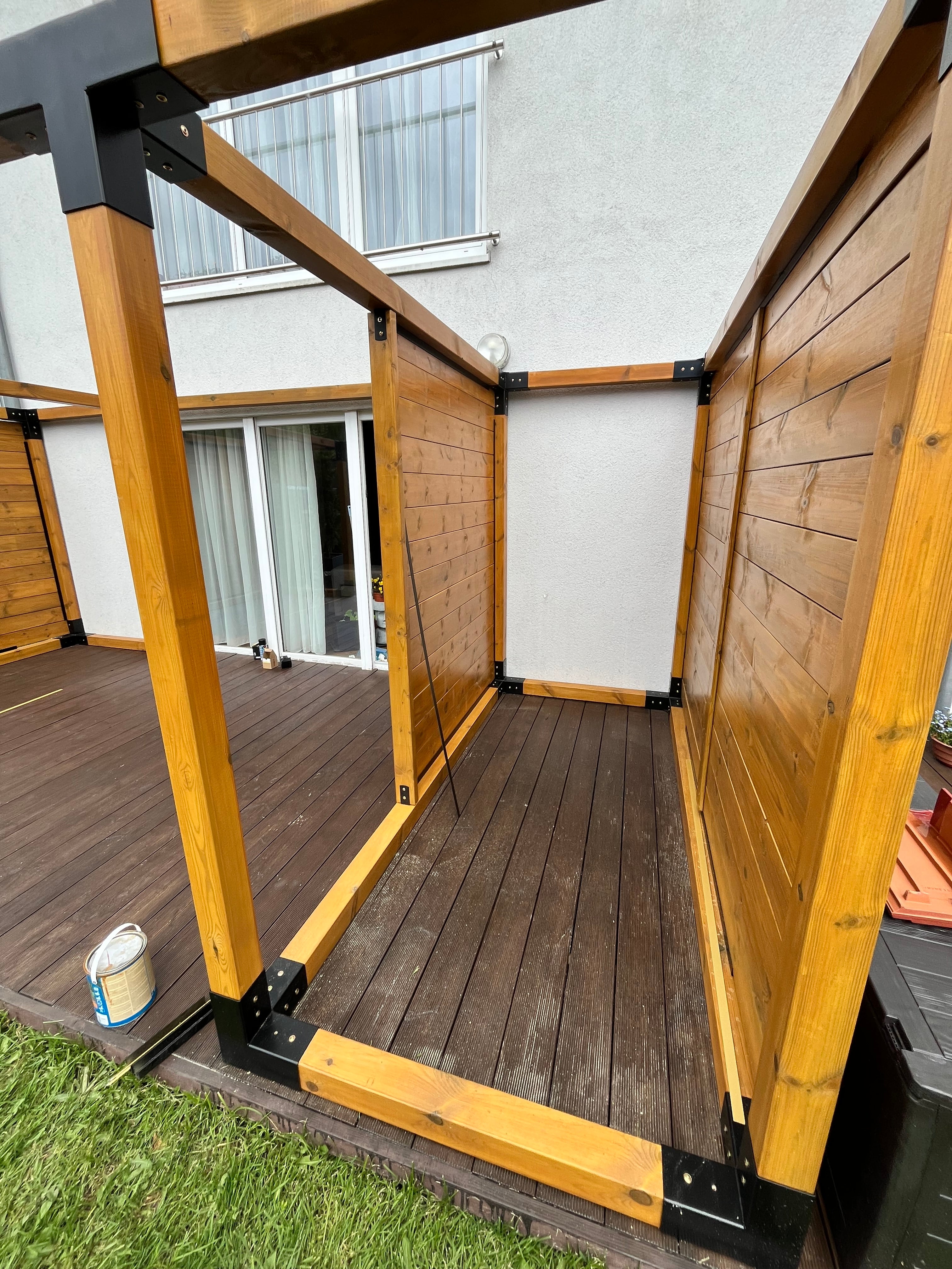 Wooden outdoor furniture with a white wall and grass in the background