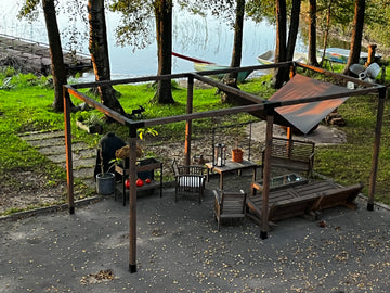 Outdoor patio area with wooden furniture and canopy near a body of water.