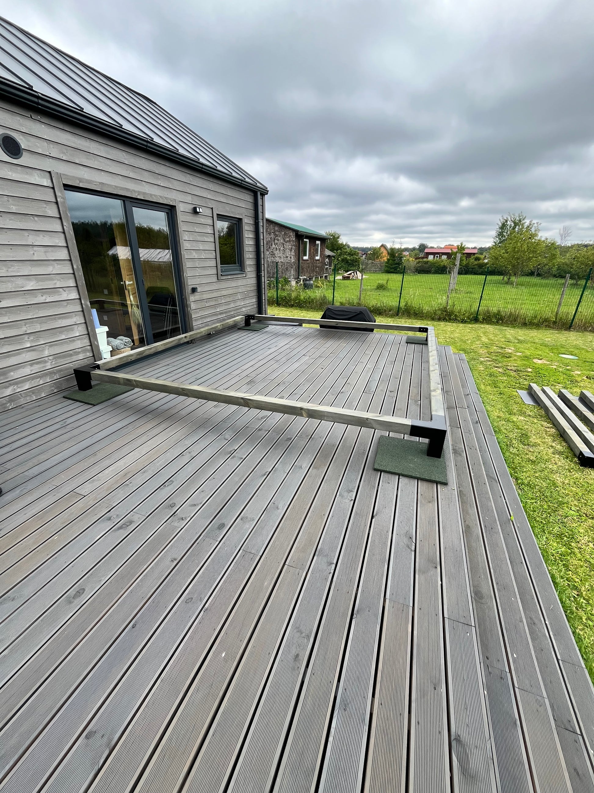 Wooden deck with a view of a house and greenery on a cloudy day