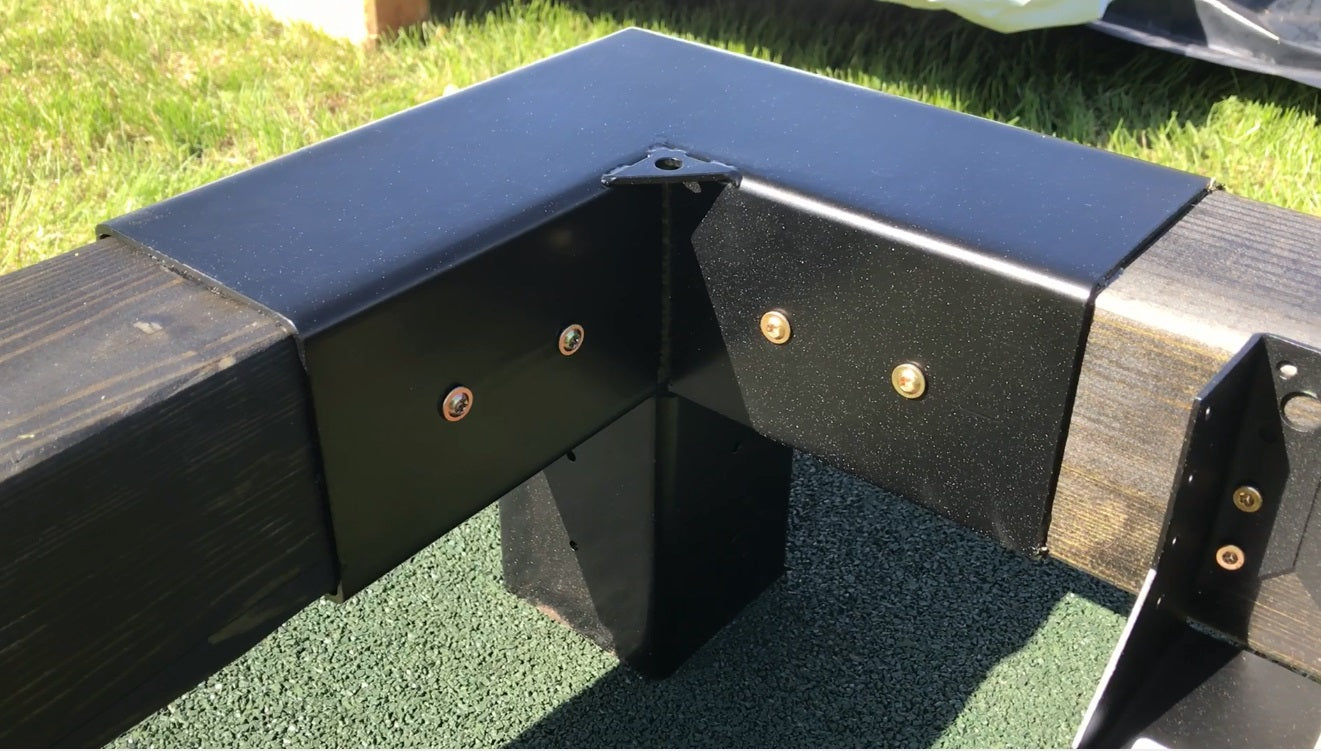 Metal bracket with wooden ends on a grassy background