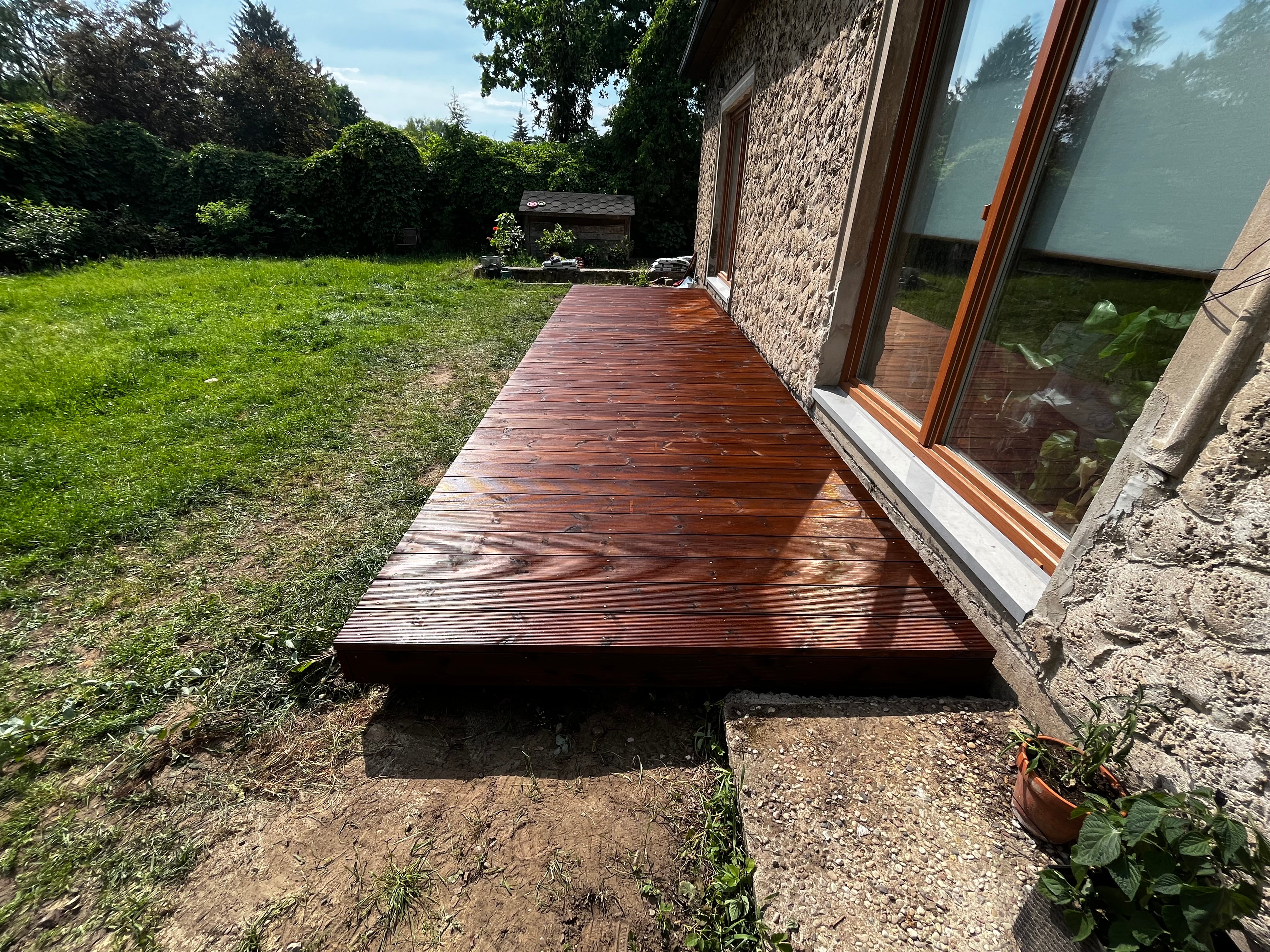 Wooden deck extending from a stone building into a grassy area