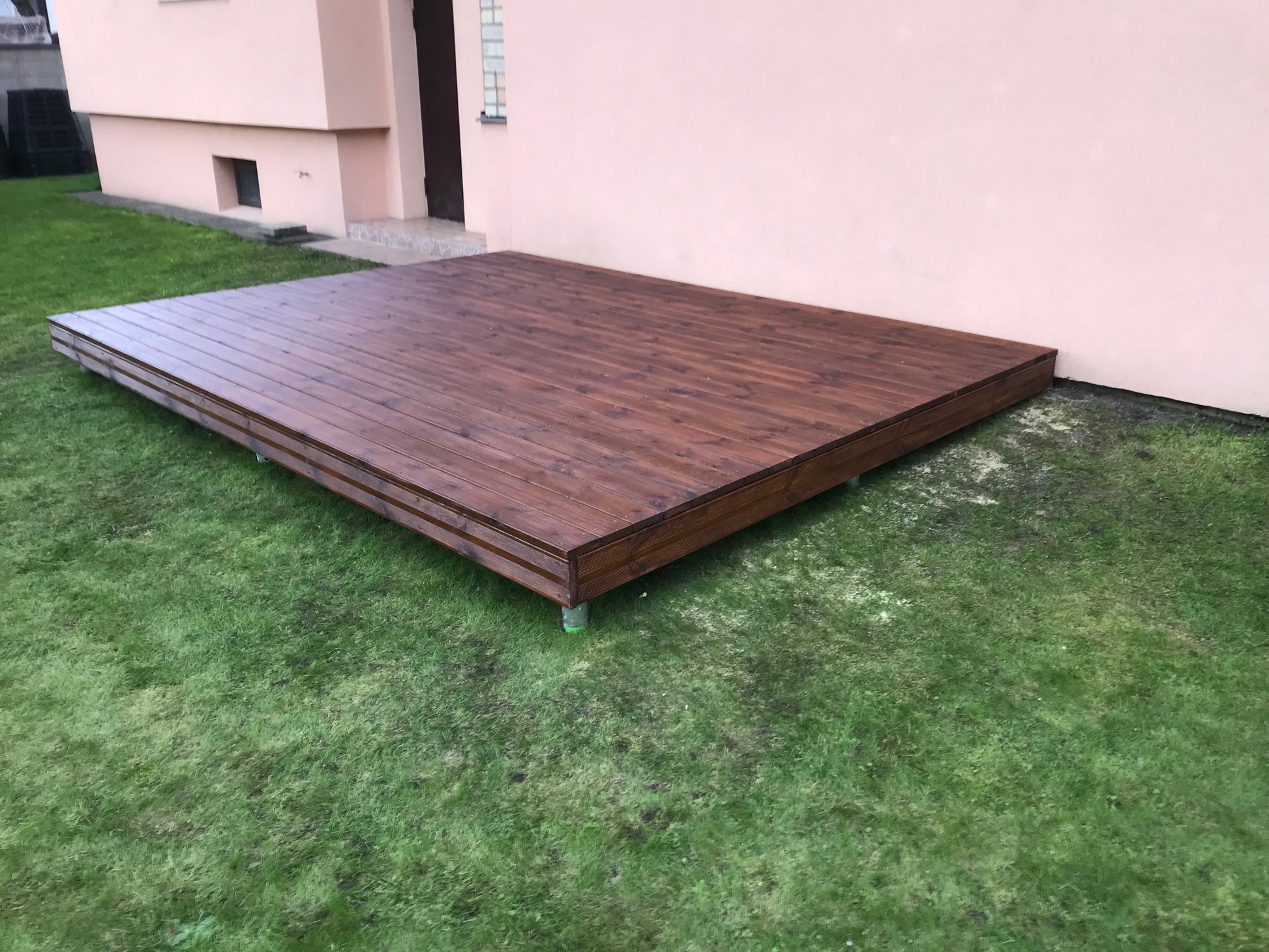 Wooden deck on grass in front of a building
