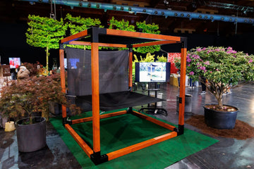 Orange and black hammock setup with screens in an indoor setting with plants and furniture.