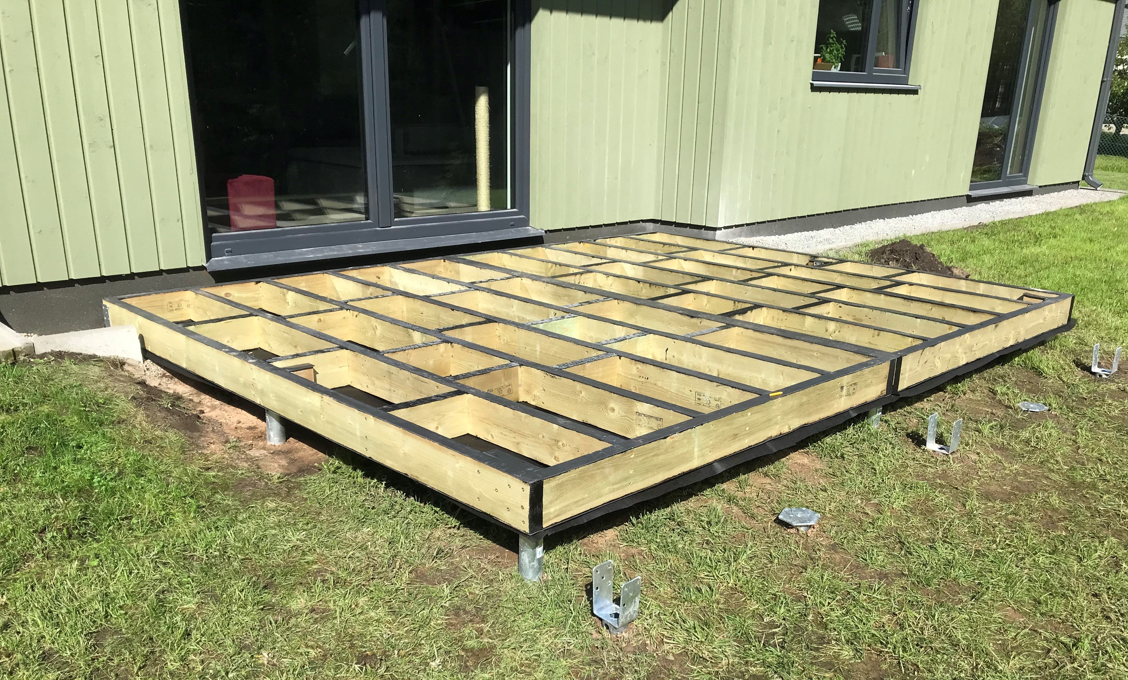 Wooden deck foundation being built in front of a modern house.