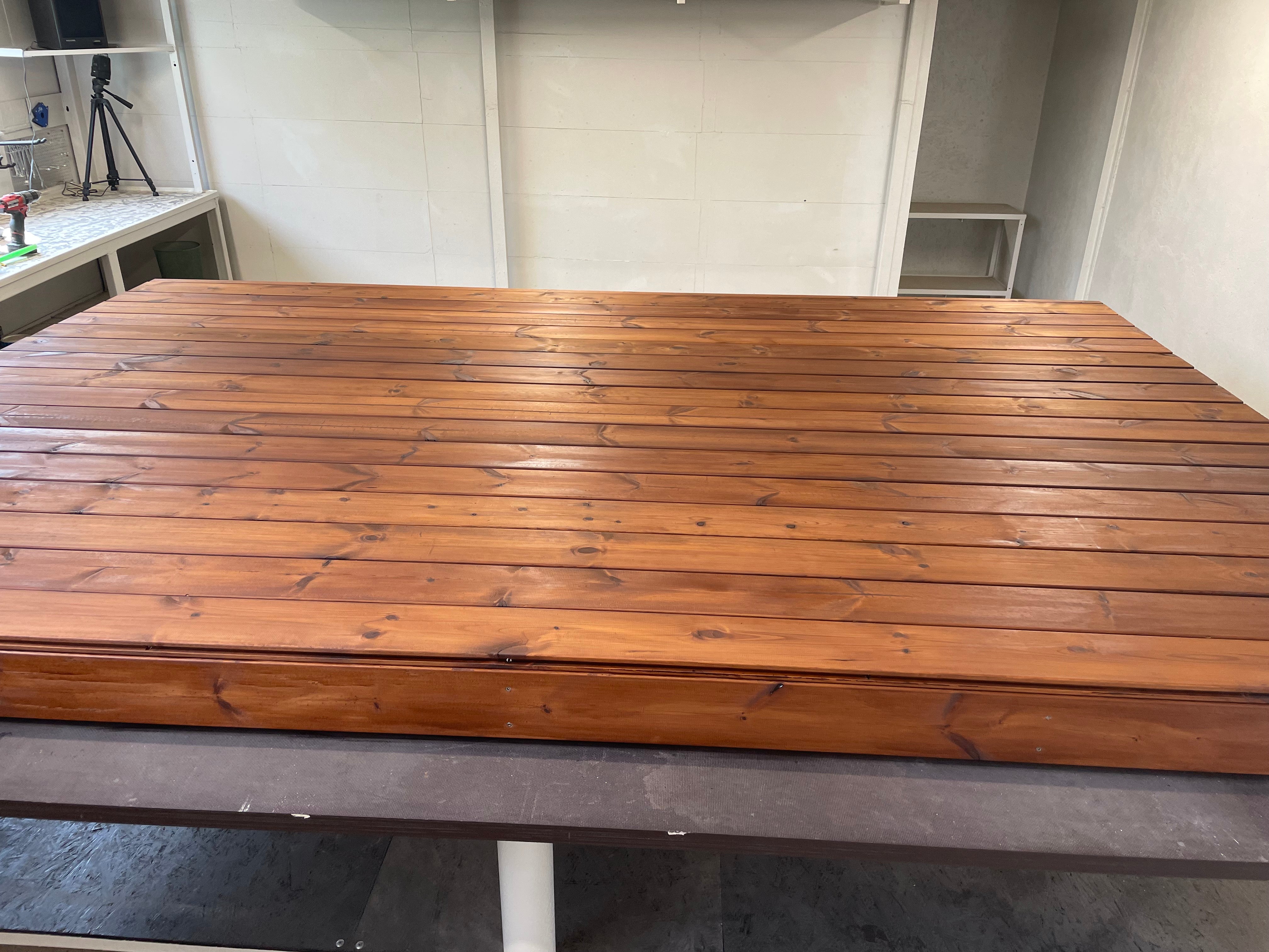 Wooden table in a room with shelves and a white wall.