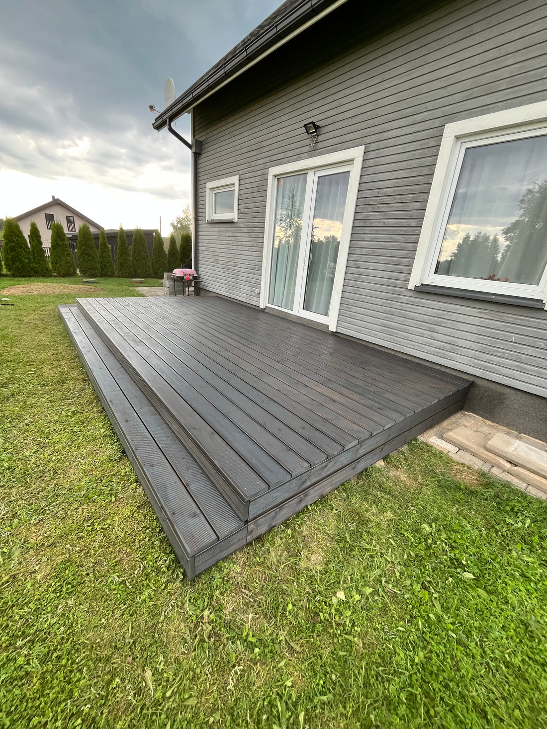 Wooden deck extension on a house with grass and sky in the background