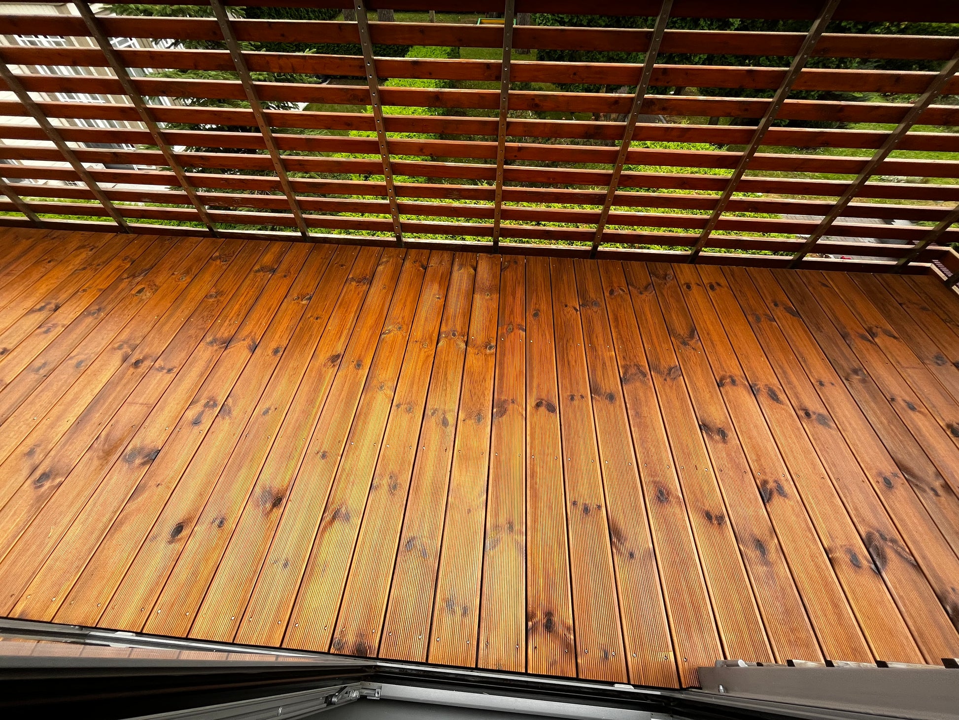 Wooden deck with a lattice roof, showing signs of wear.