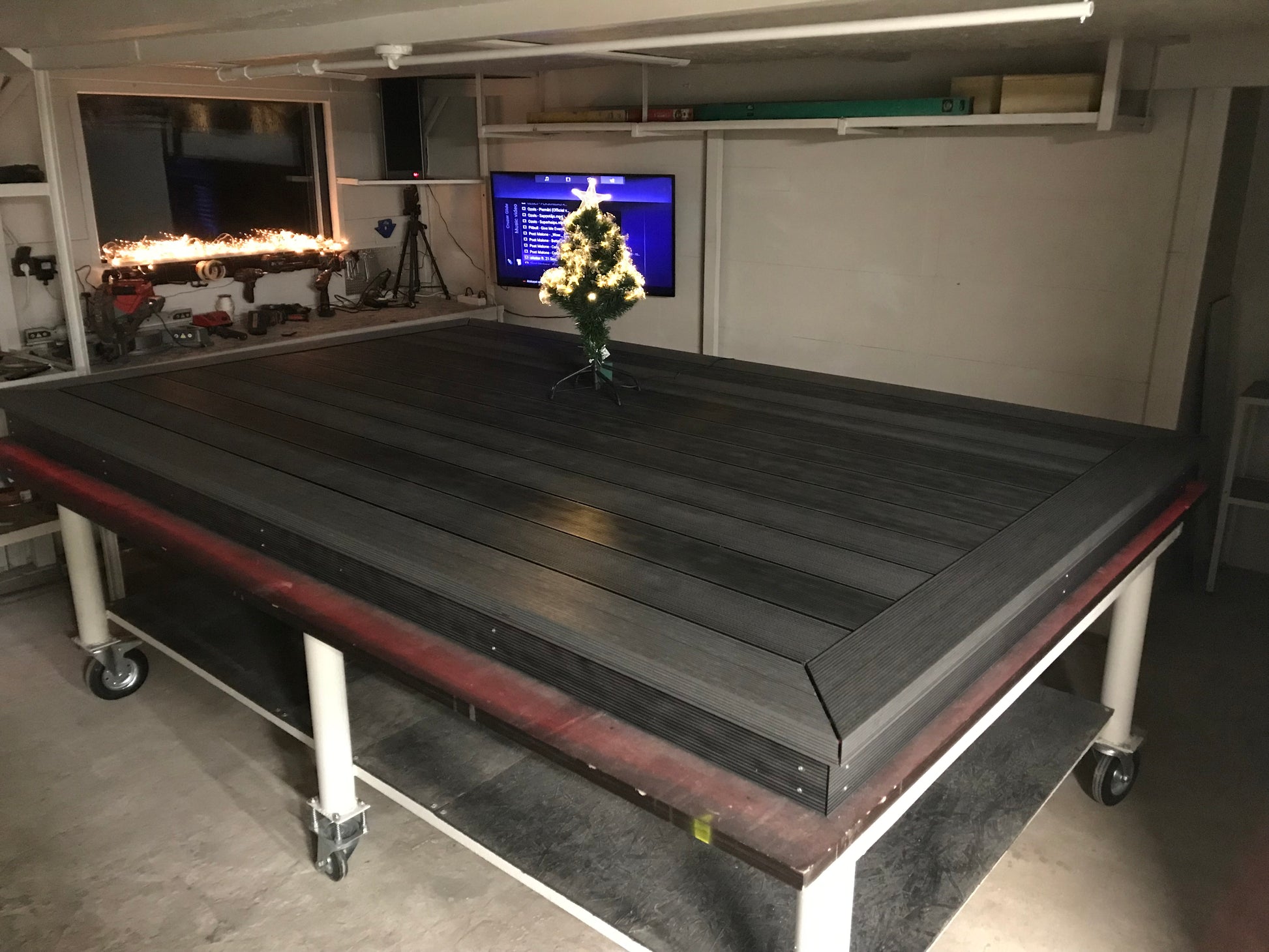 Large black flatbed truck in a workshop setting with tools and equipment in the background.