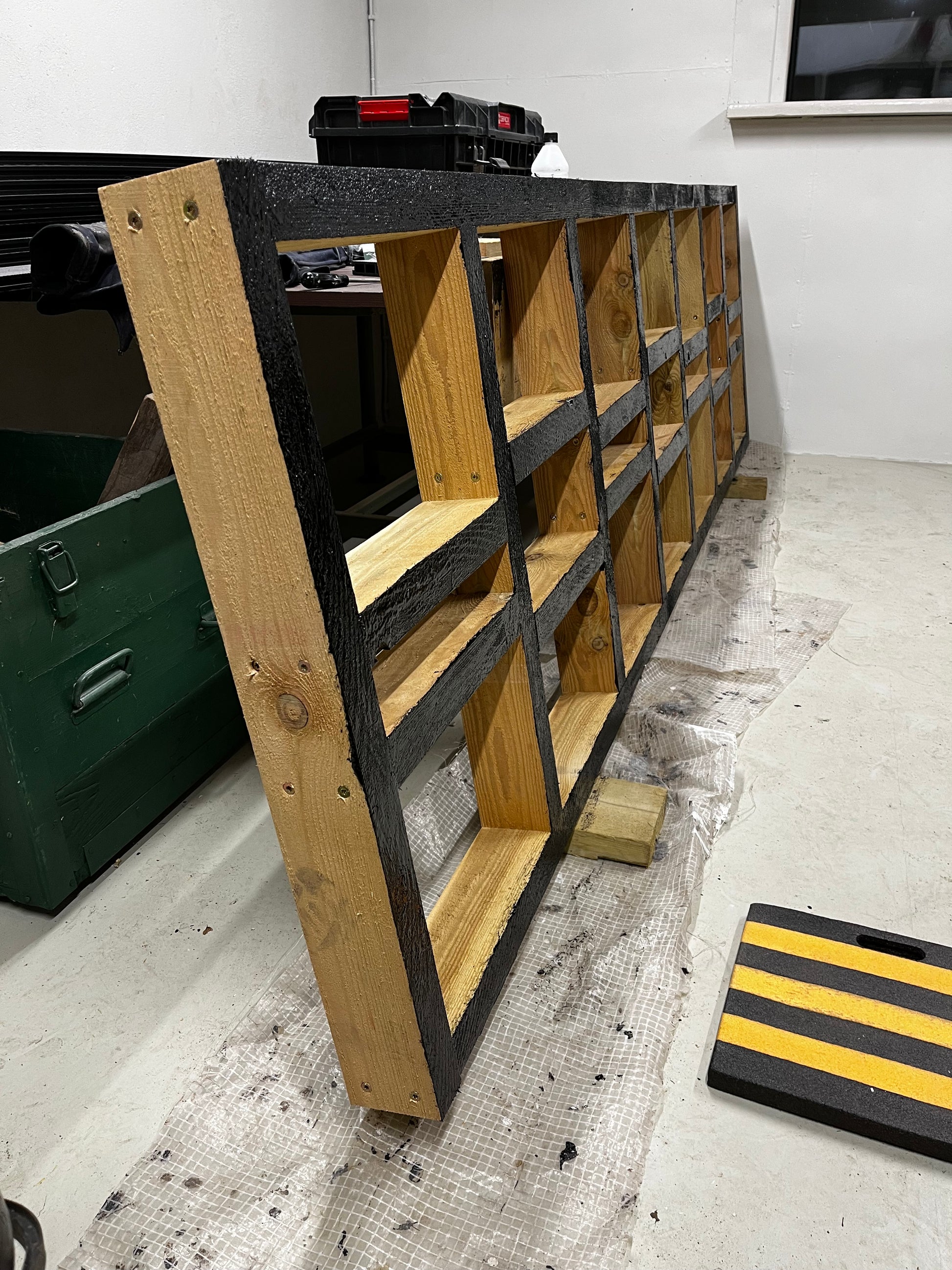 Wooden storage shelf with black border on a concrete floor.