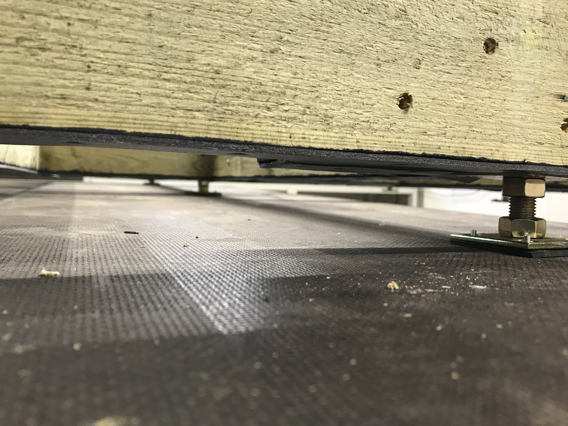 Close-up of a metal frame with insulation material on a textured floor.